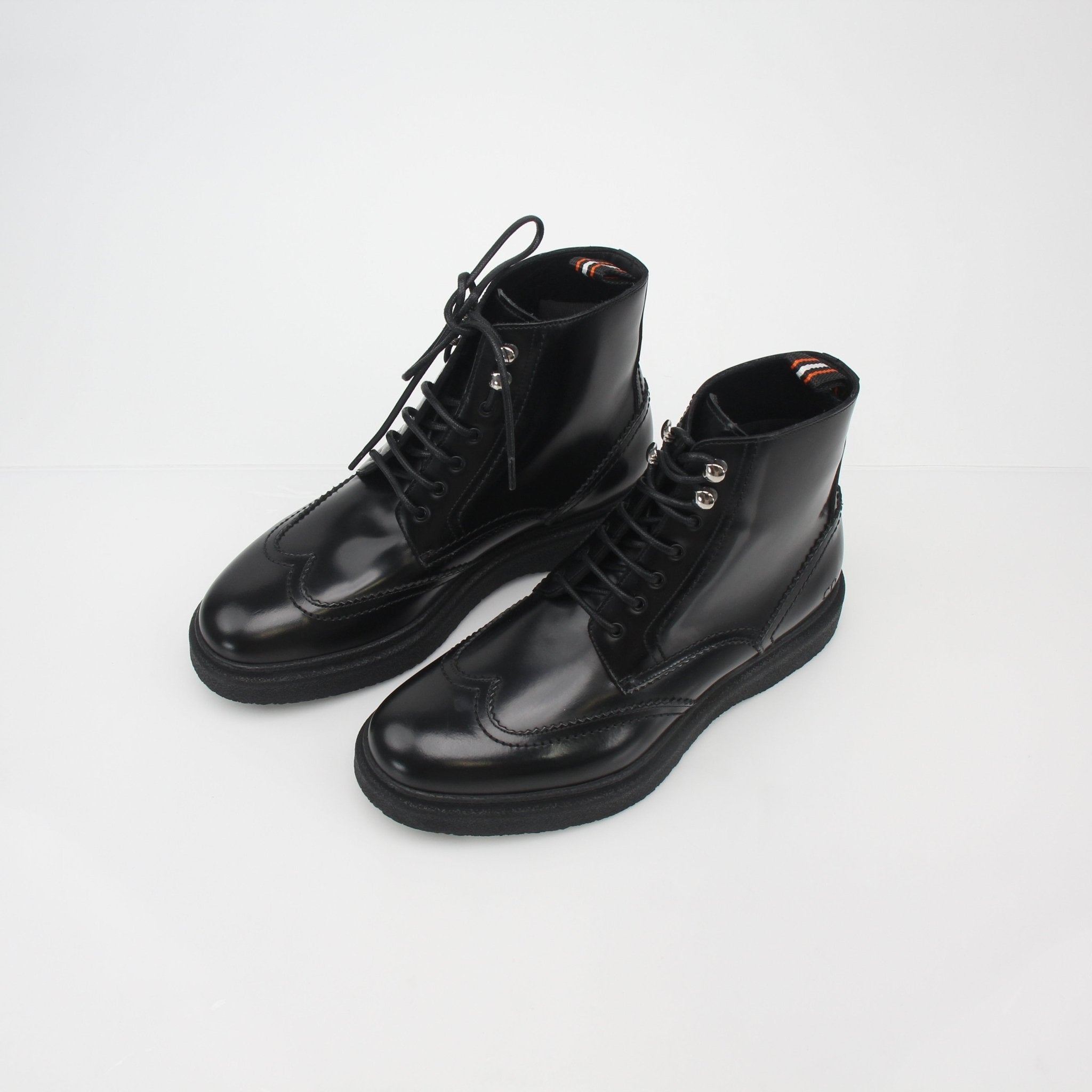 Christian Dior black leather wingtip combat ankle boots, stylish shoes with detailed wingtip design and sturdy sole.