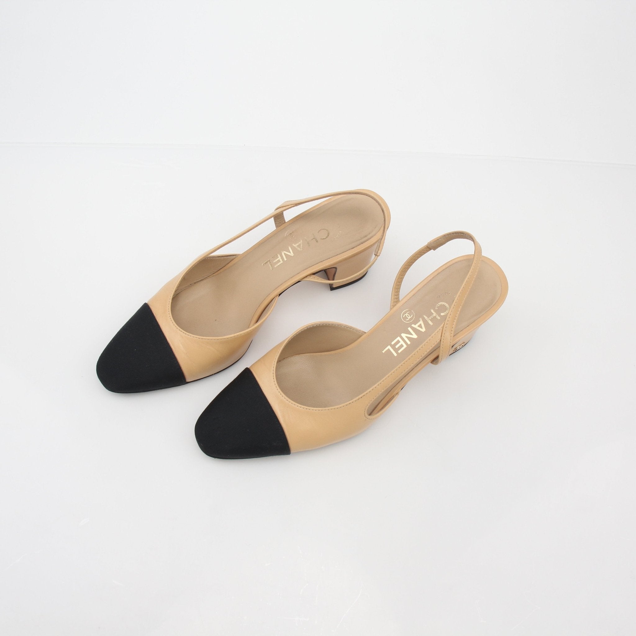 Gold & Beyond beige and black Chanel-style cap-toe slingback pumps featuring classic heels and elegant design.