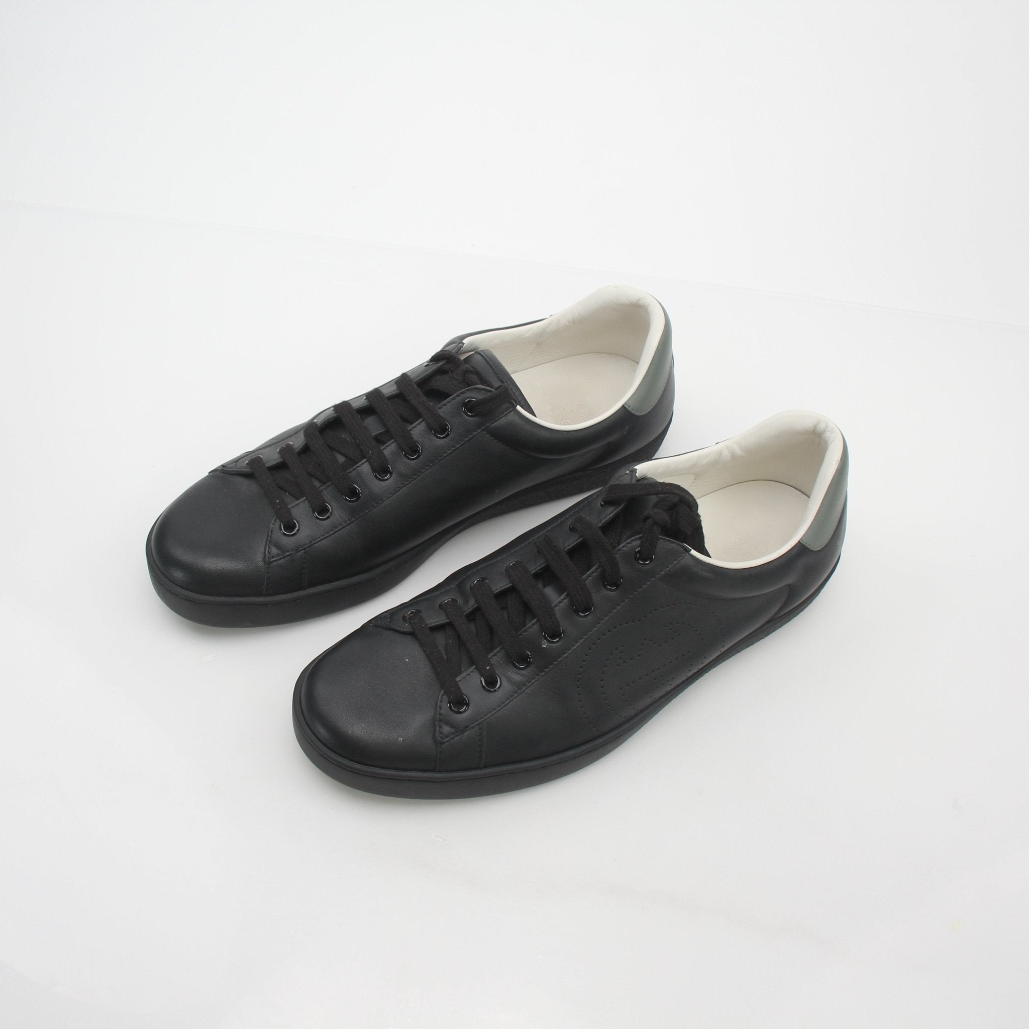 Gucci Black Ace perforated leather sneakers with interlocking G design, showcased from a side angle.