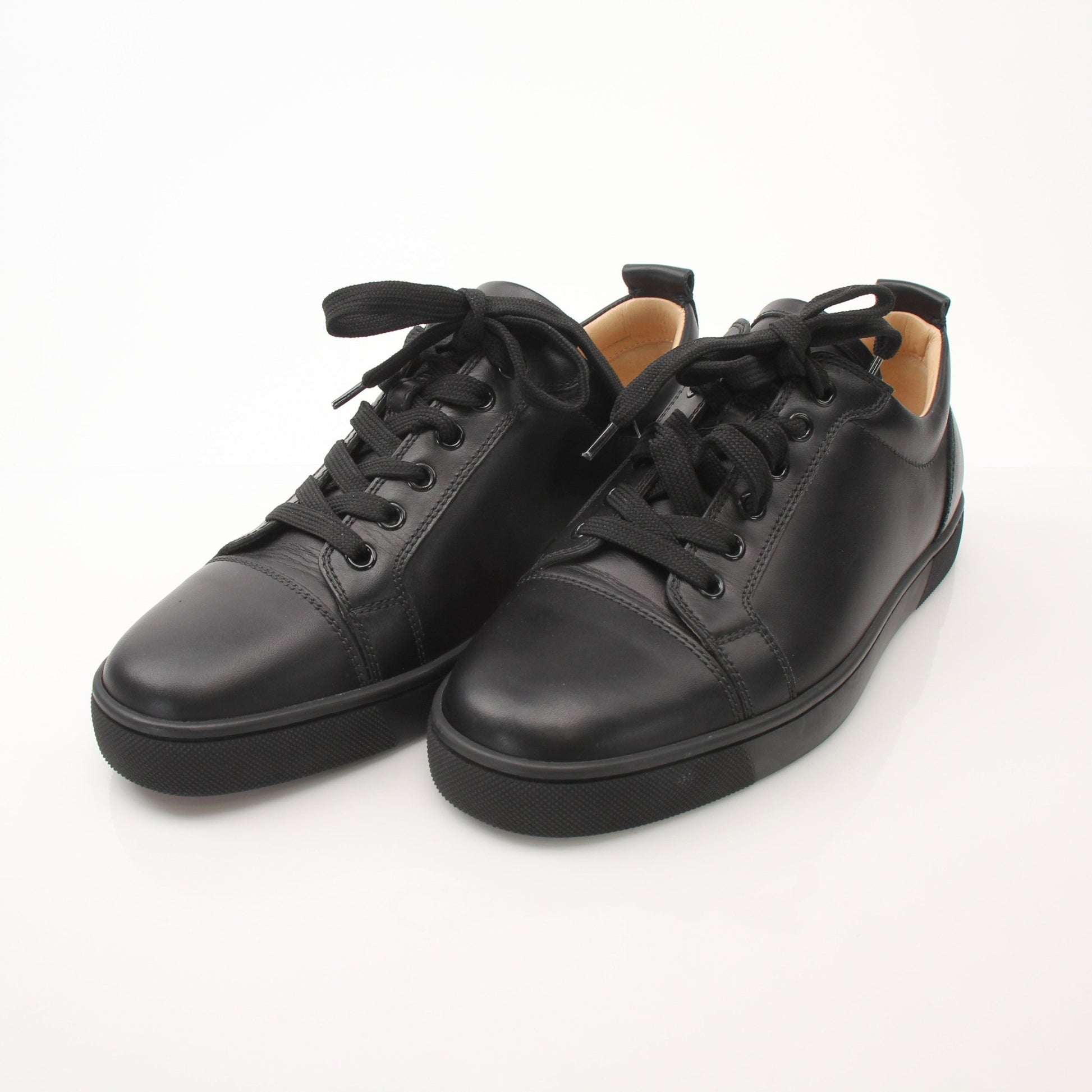 Christian Louboutin Louis Junior sneakers in black with signature red soles, displayed on a neutral background.