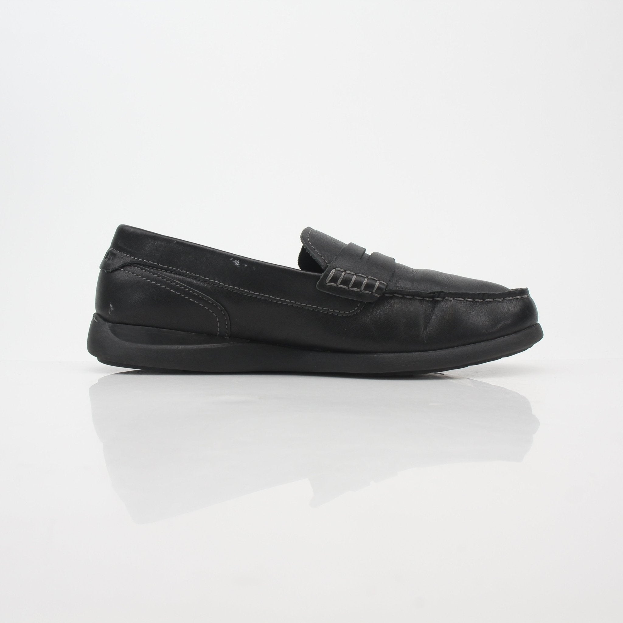 Black leather Cole Haan Grand Atlantic penny loafers worn on feet, showcasing classic slip-on shoes with a sleek design.