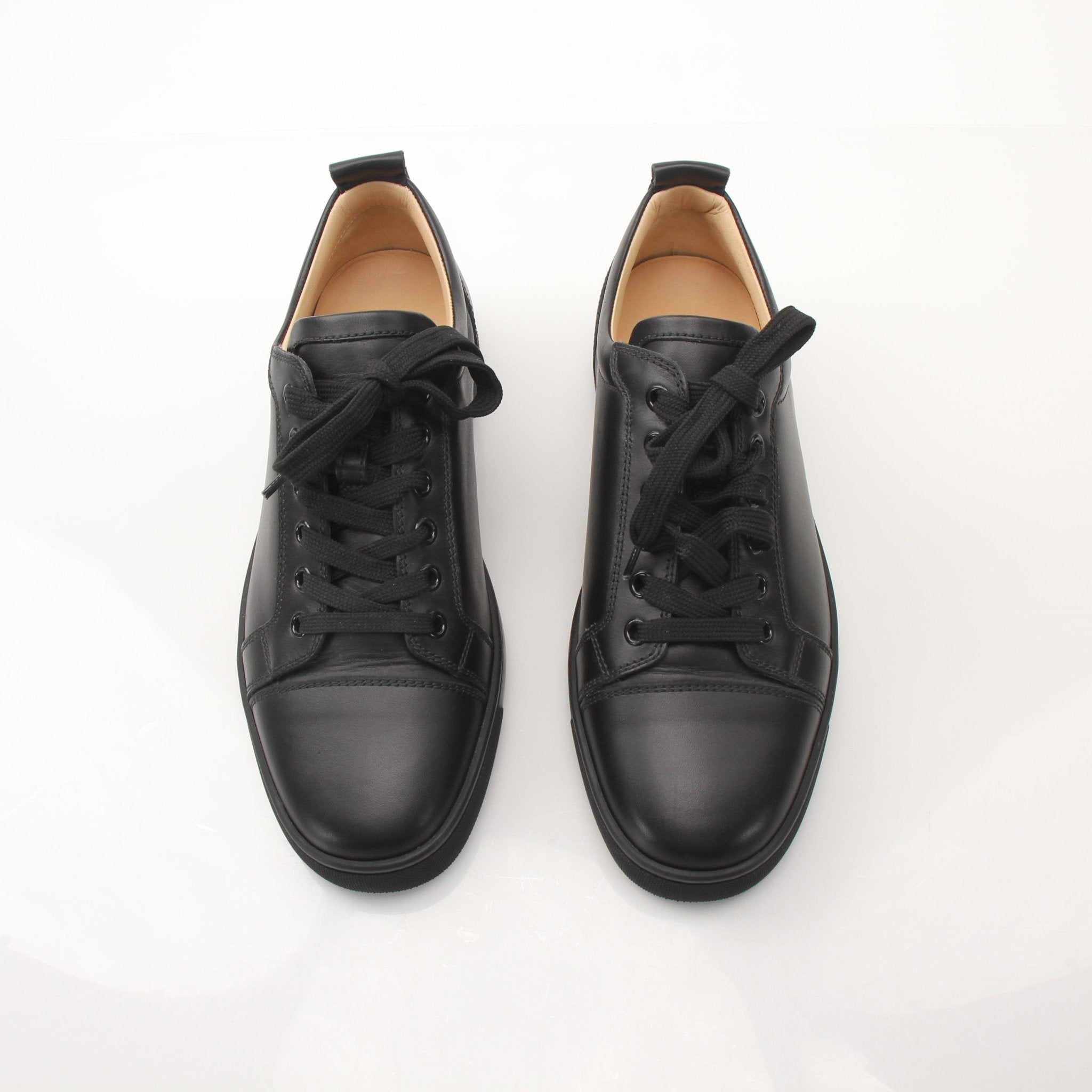 Christian Louboutin Louis Junior sneakers in black with signature red soles, showcased on a neutral background.