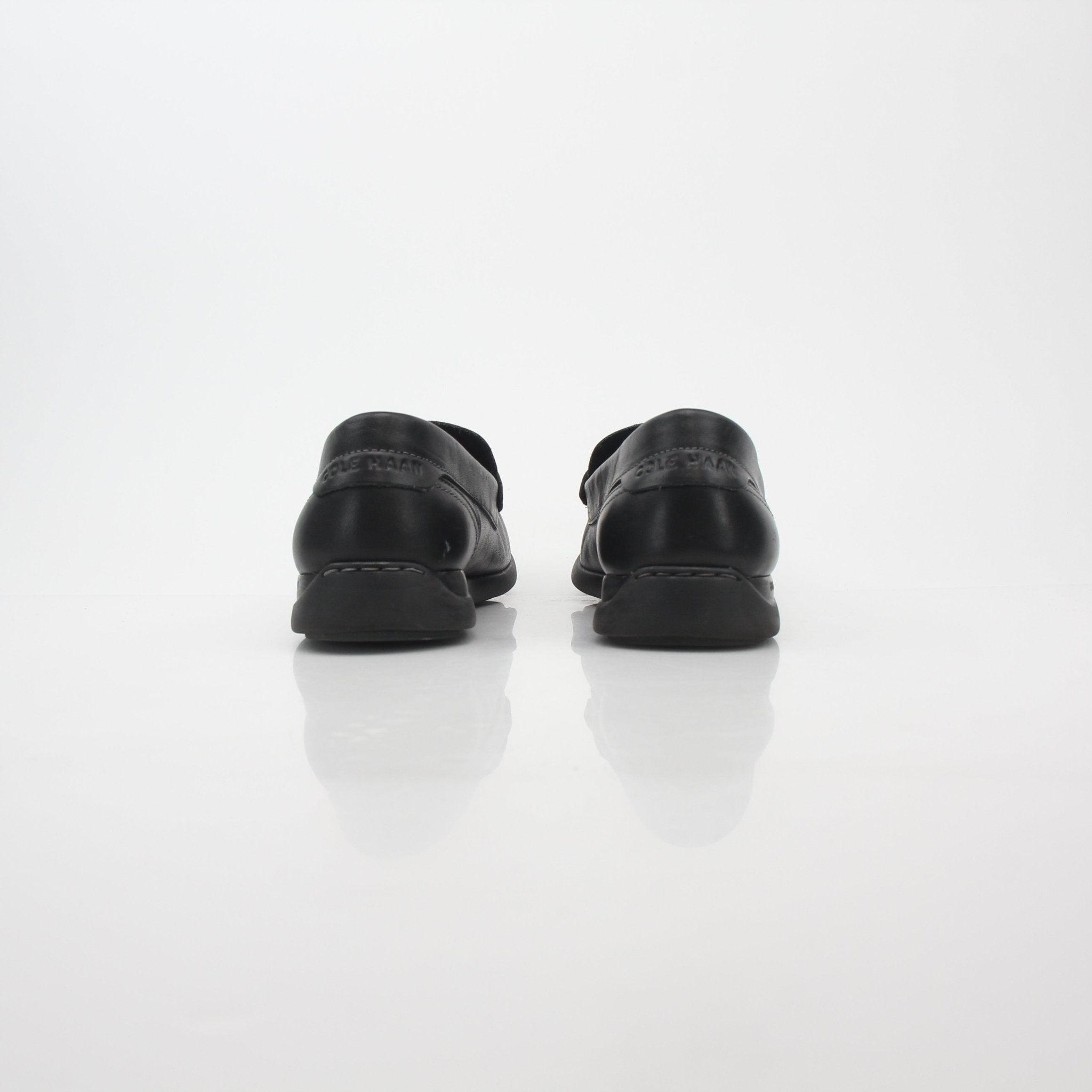 Black leather Cole Haan Grand Atlantic penny loafers for men, showcasing classic slip-on shoes with a sleek design.