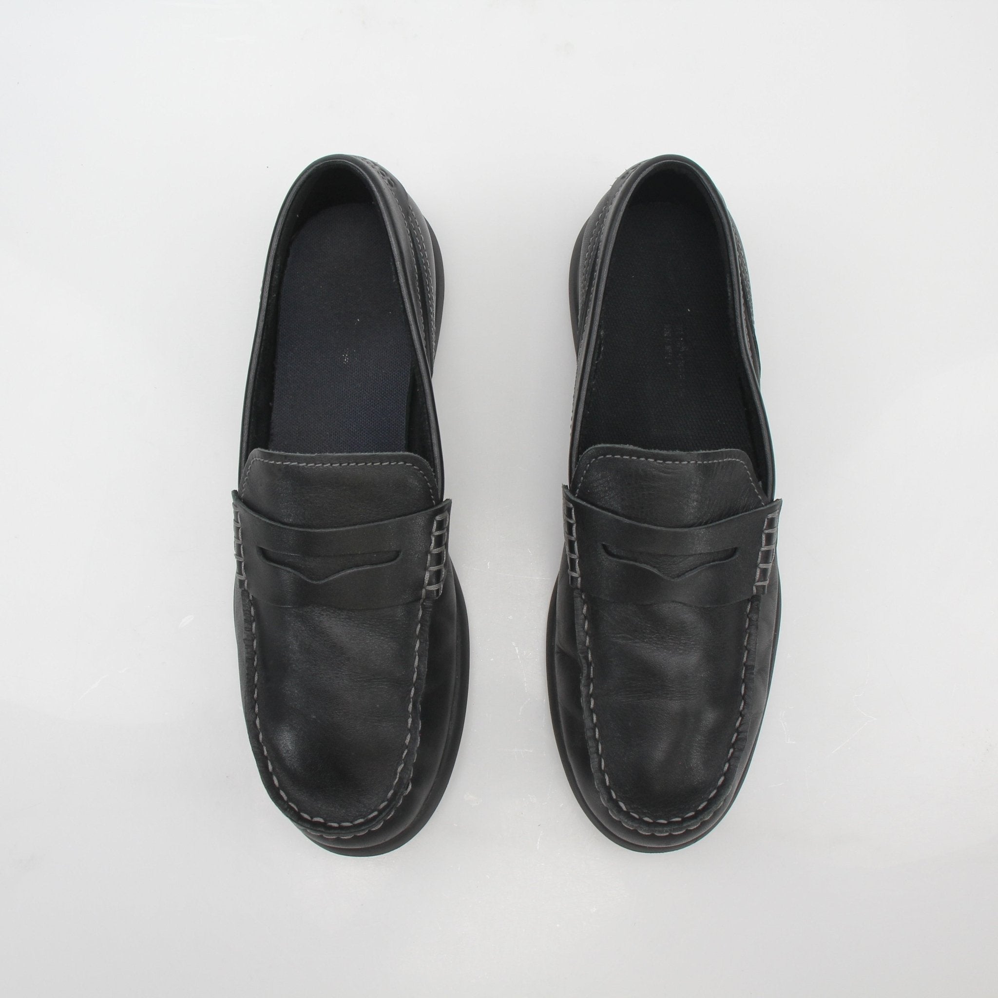 Cole Haan Grand Atlantic black leather penny loafers, men's shoes, showcasing smooth leather upper and classic slip-on design.