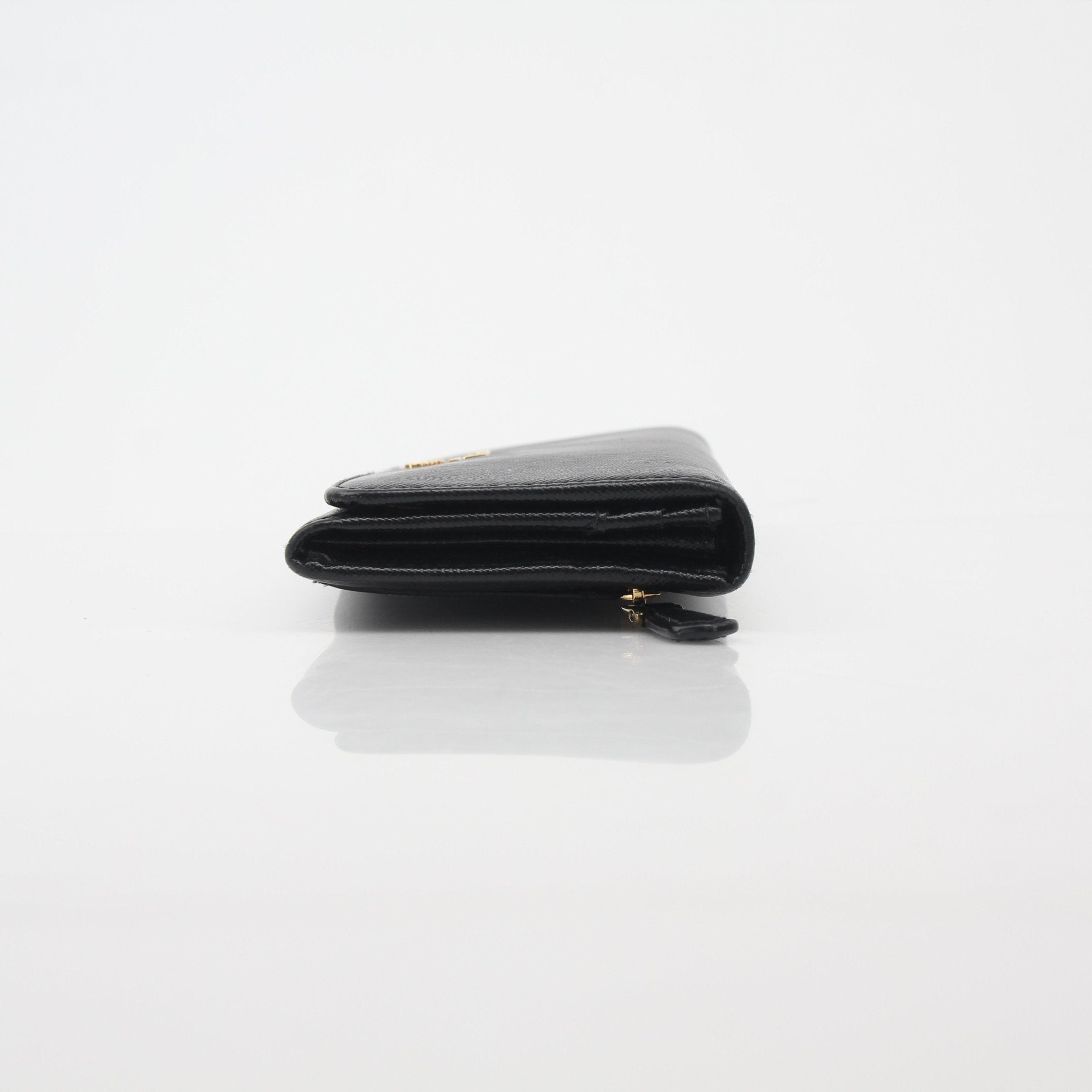 Prada black saffiano leather continental wallet with gold-tone hardware and multiple card slots, shown open with interior details.