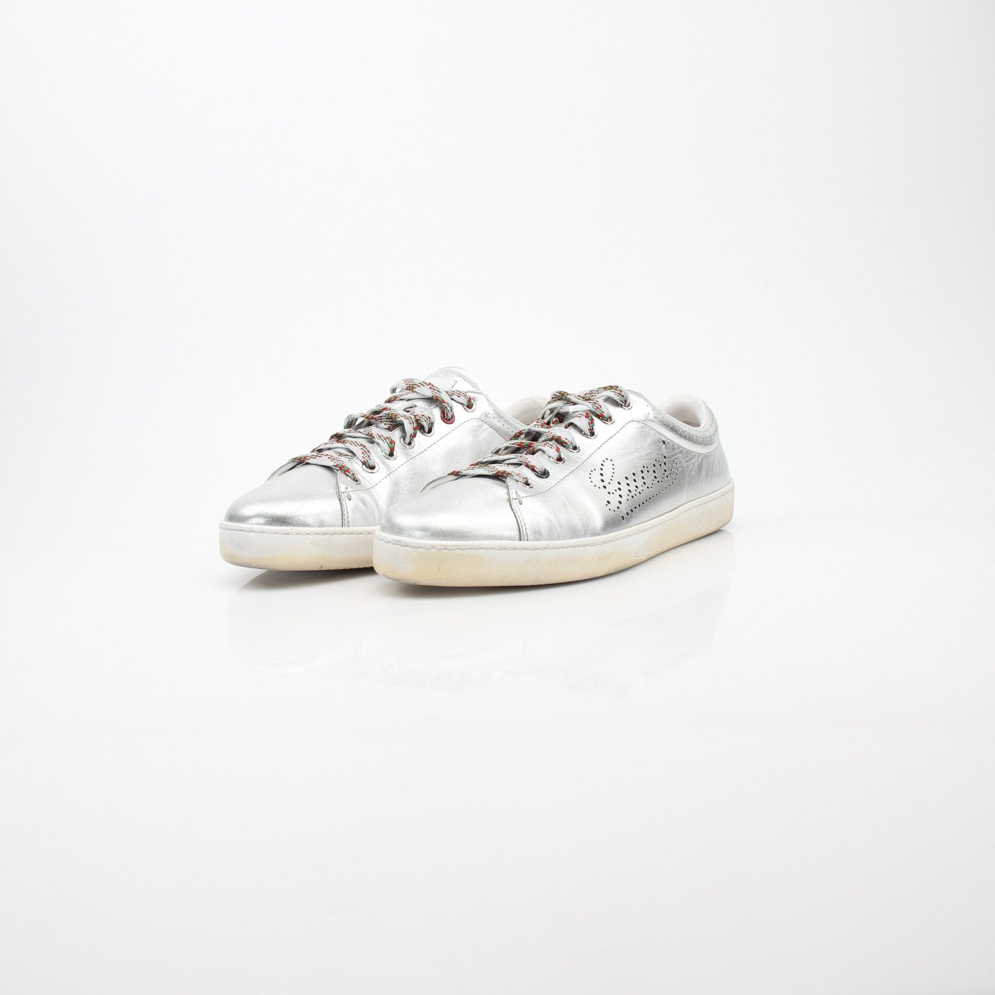 Gucci silver metallic Ace perforated logo sneakers with white soles and stylish design, displayed on a plain background.