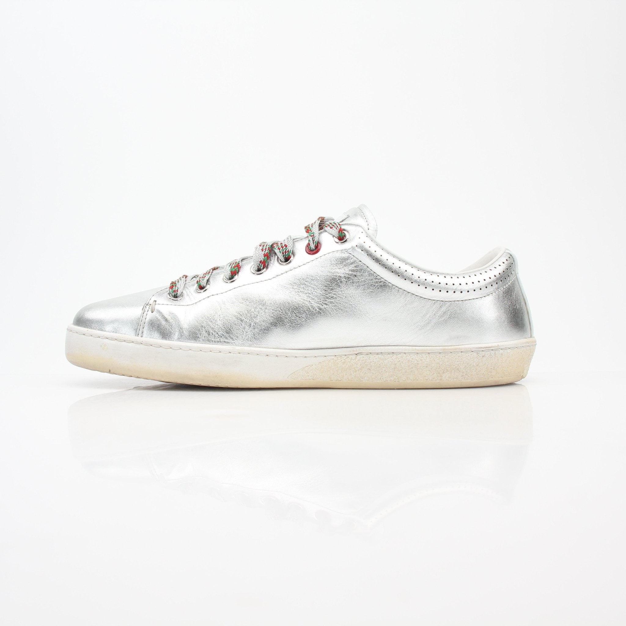 Silver metallic Gucci Ace sneakers with perforated logo design, featuring a sleek, stylish shoe with white rubber sole and iconic branding.