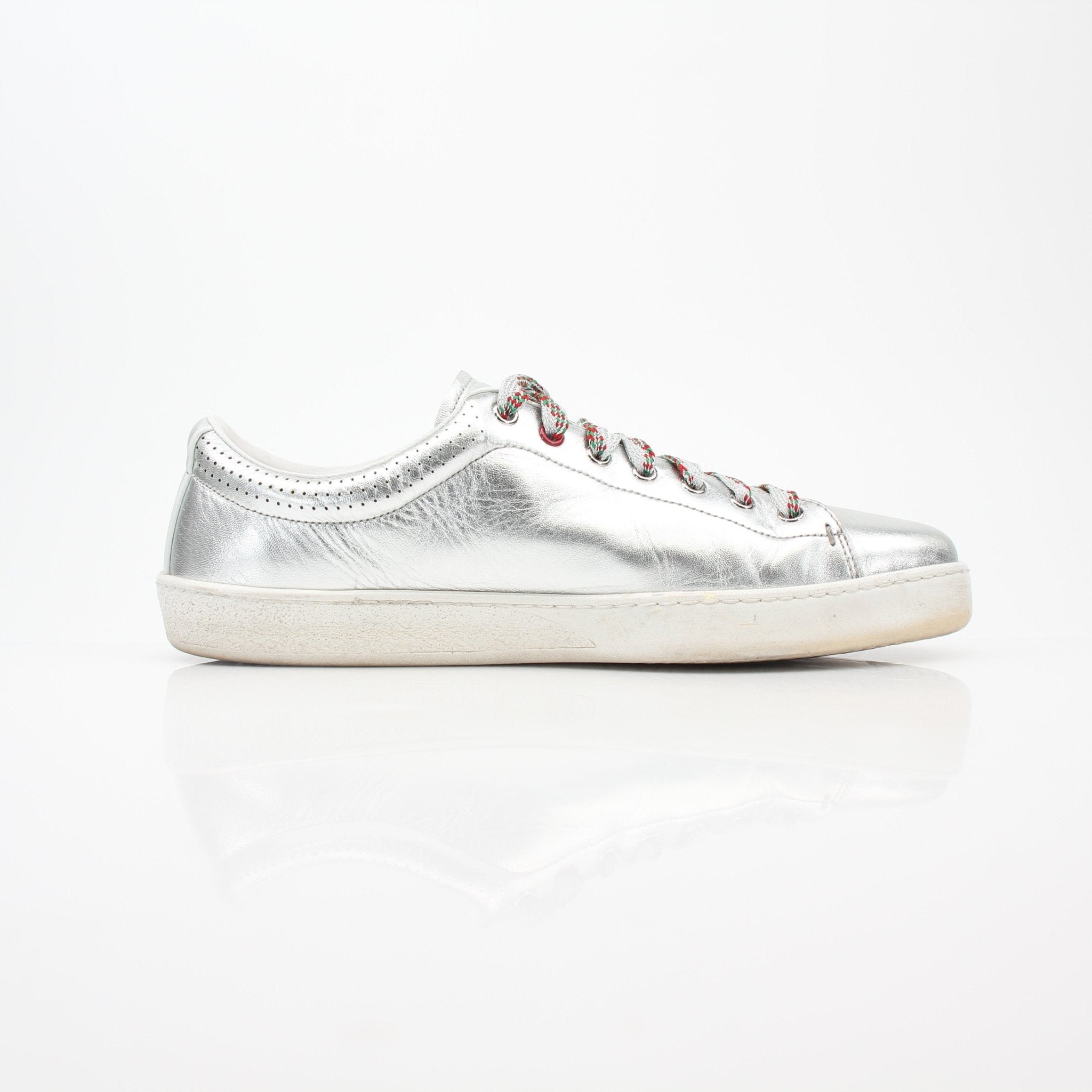 Gucci silver metallic Ace perforated logo sneakers with white soles, showcasing stylish, perforated design and brand details.