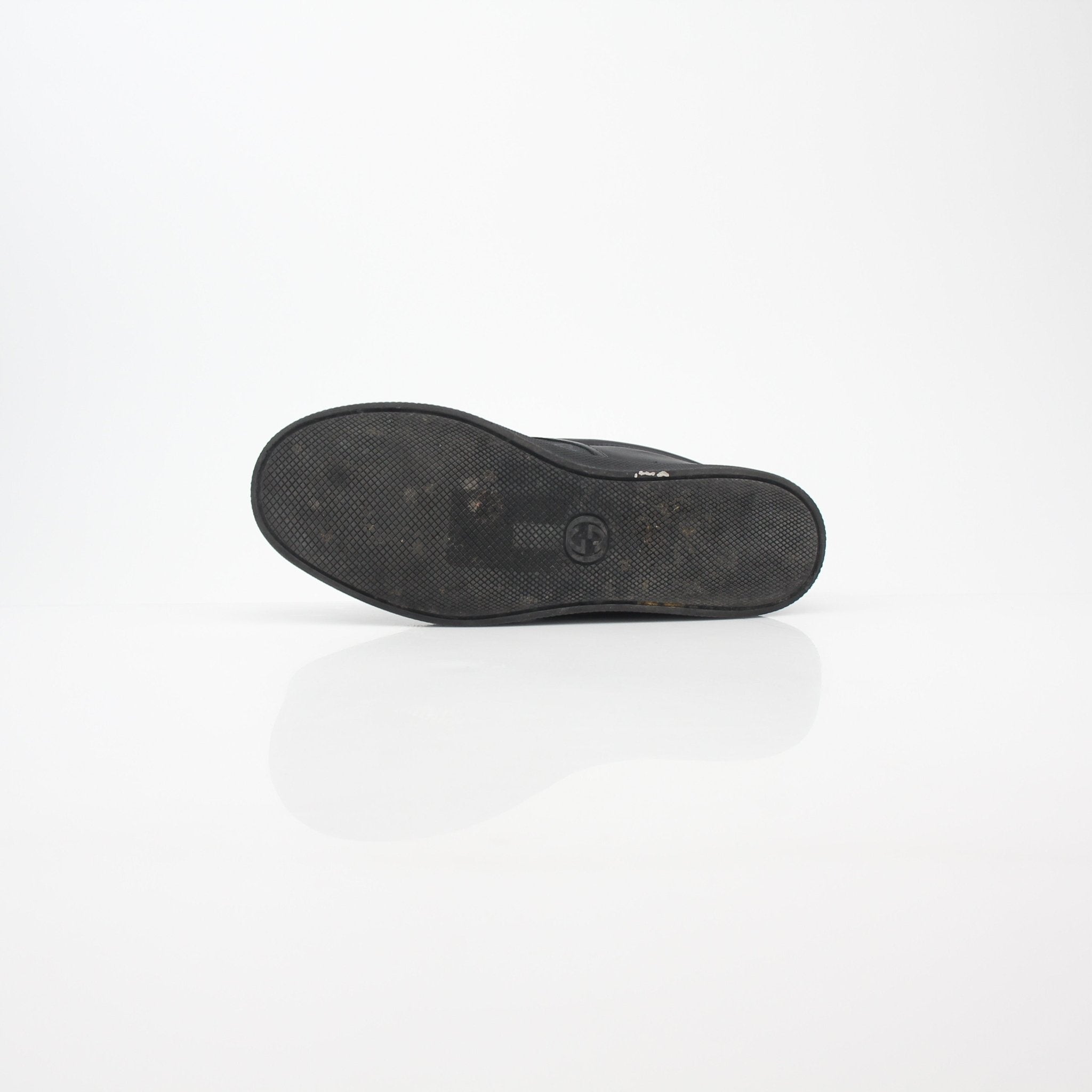 Gucci black GG Supreme Dublin slip-on sneakers with white soles and gold accents, displayed on a plain background.