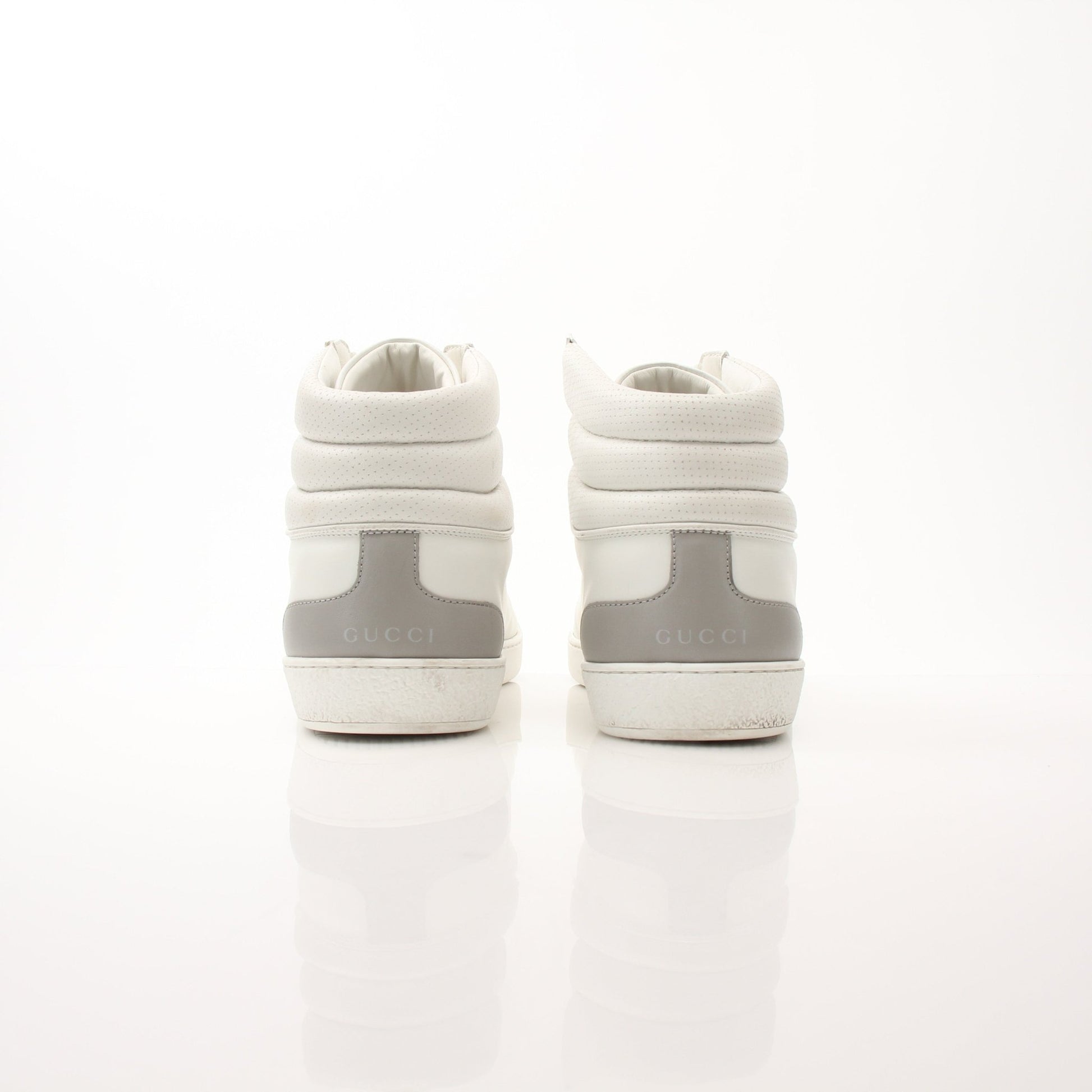 Gold & Beyond Gucci Ace high top sneakers showing white canvas with Gucci logo details and rubber sole.