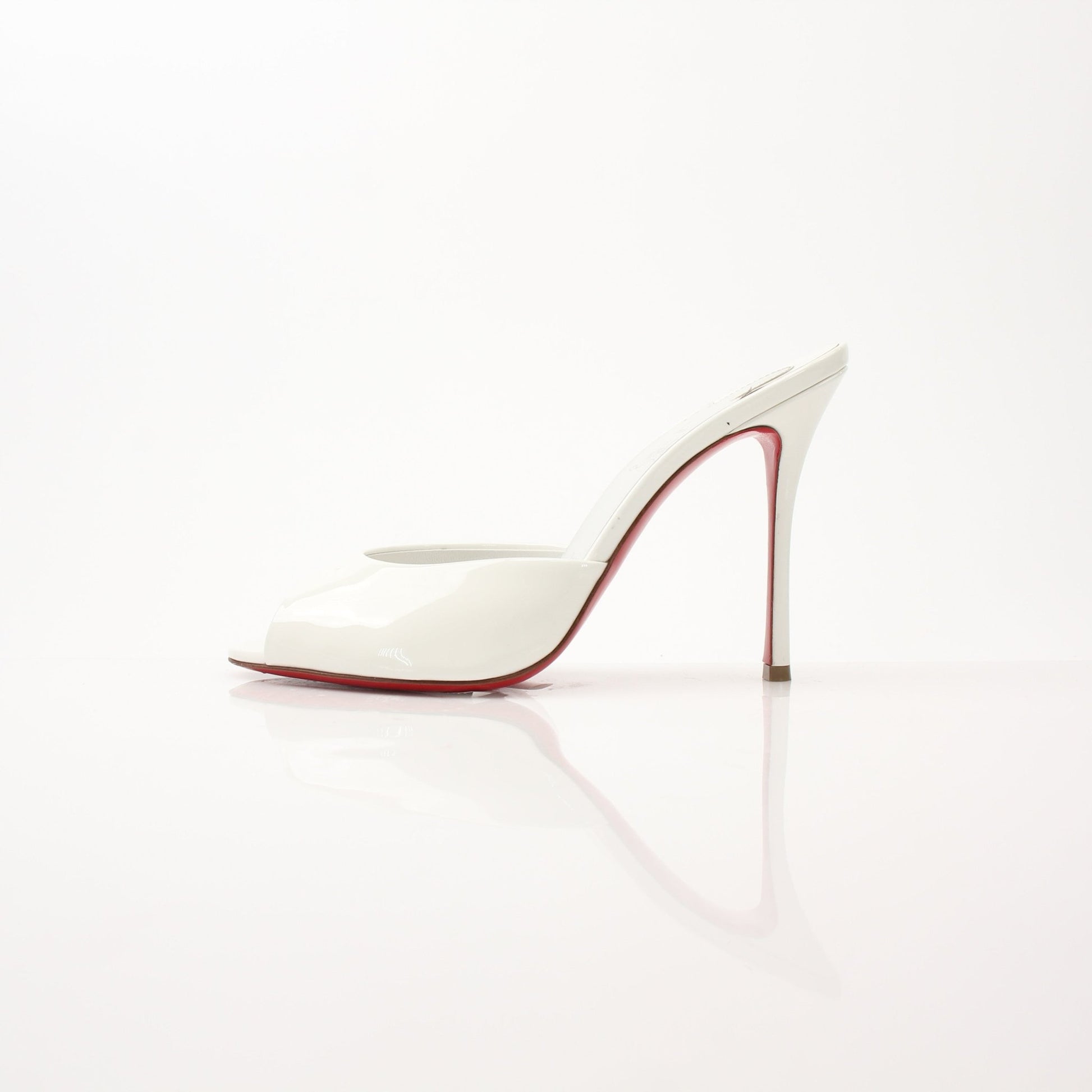 Christian Louboutin White Me Dolly Mules shoes with pointed toes and signature red soles, displayed on a neutral background.