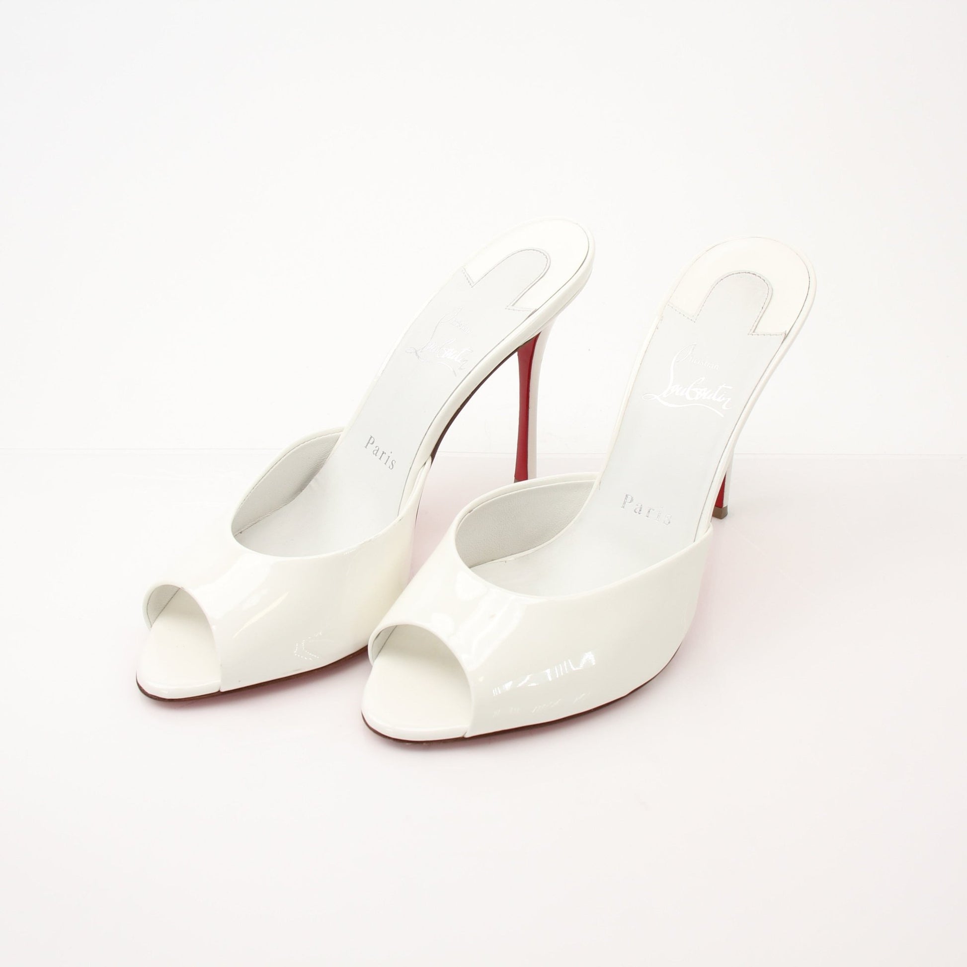 Christian Louboutin White Me Dolly Mules shoes with pointed toes and signature red soles, displayed on a neutral background.