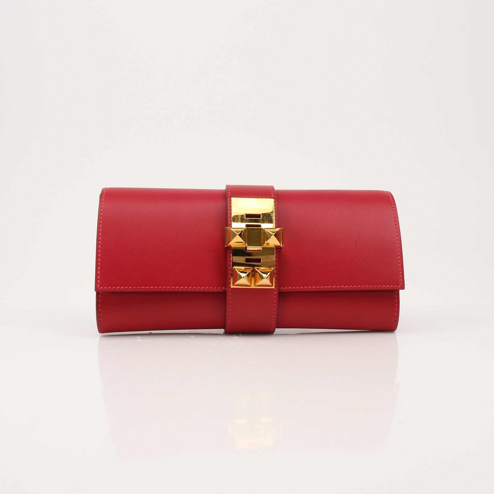 Hermès Médor 23 red clutch handbag with gold hardware, sleek design, and textured leather finish, by Gold & Beyond.