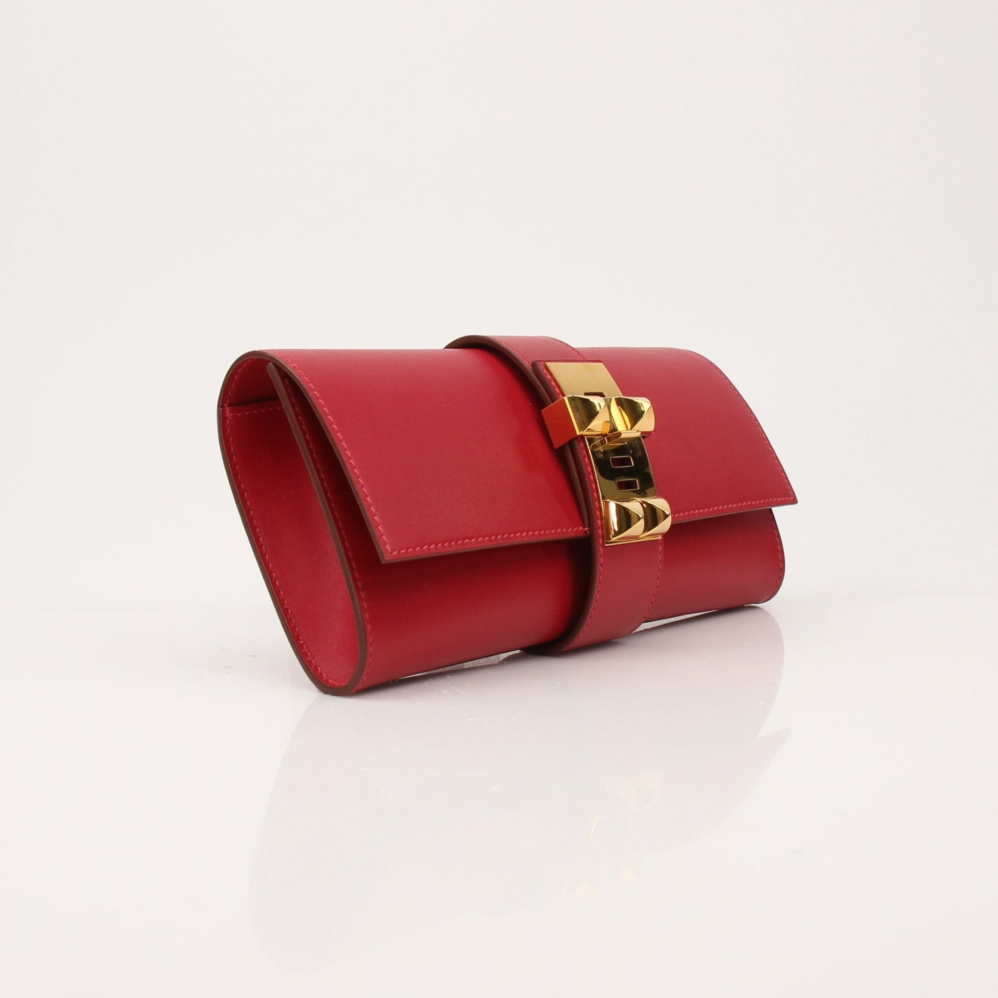 Hermès Médor 23 red leather clutch handbag with gold hardware, featuring a sleek, compact design perfect for evening occasions.