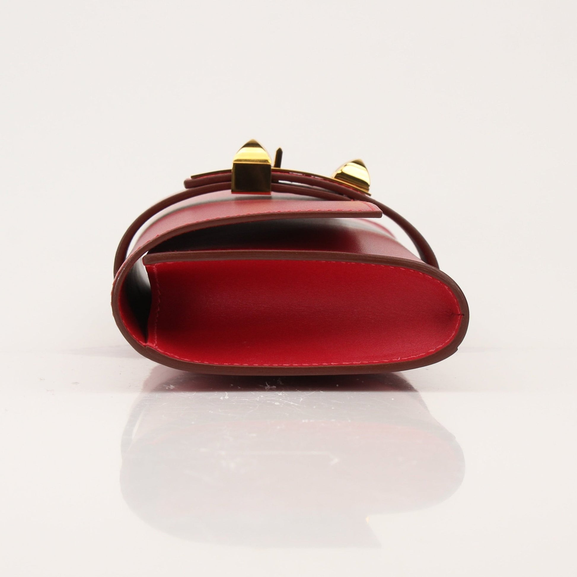 Hermès Médor 23 red leather clutch handbag with gold hardware, featuring a sleek design and compact size.