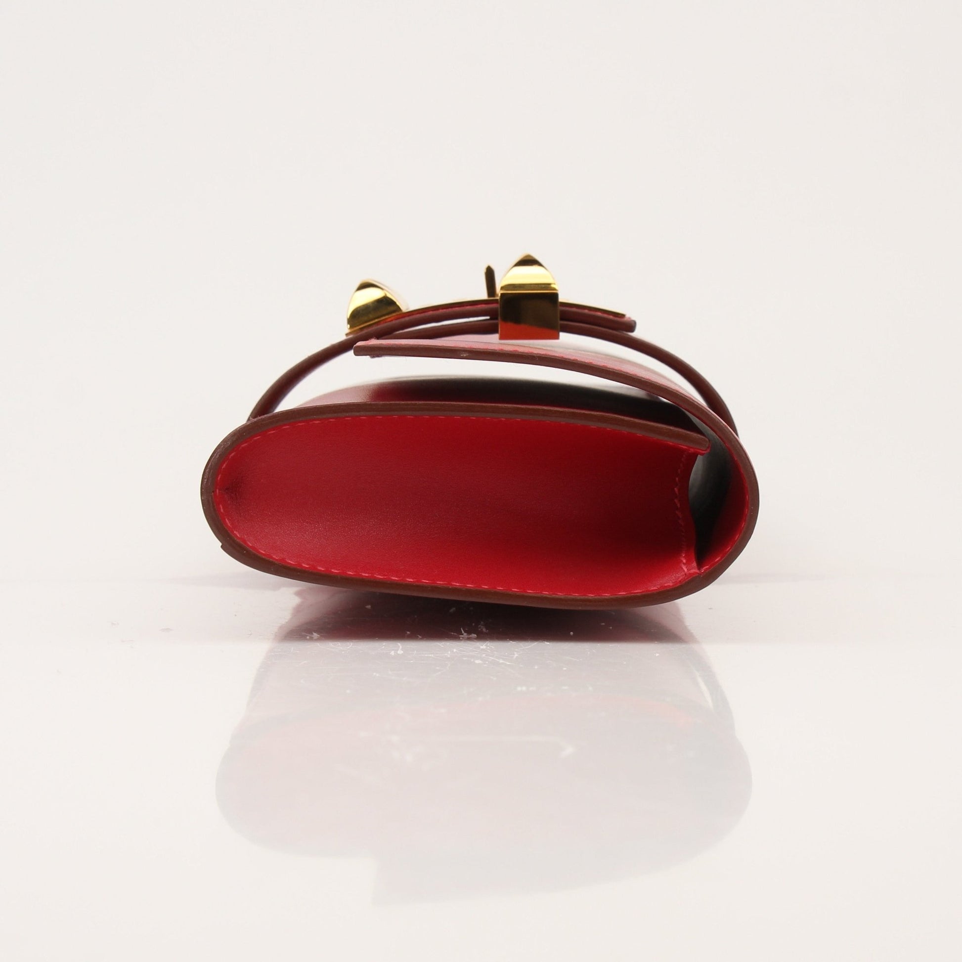Hermès Médor 23 red clutch handbag with gold hardware, featuring a sleek design and textured leather finish.