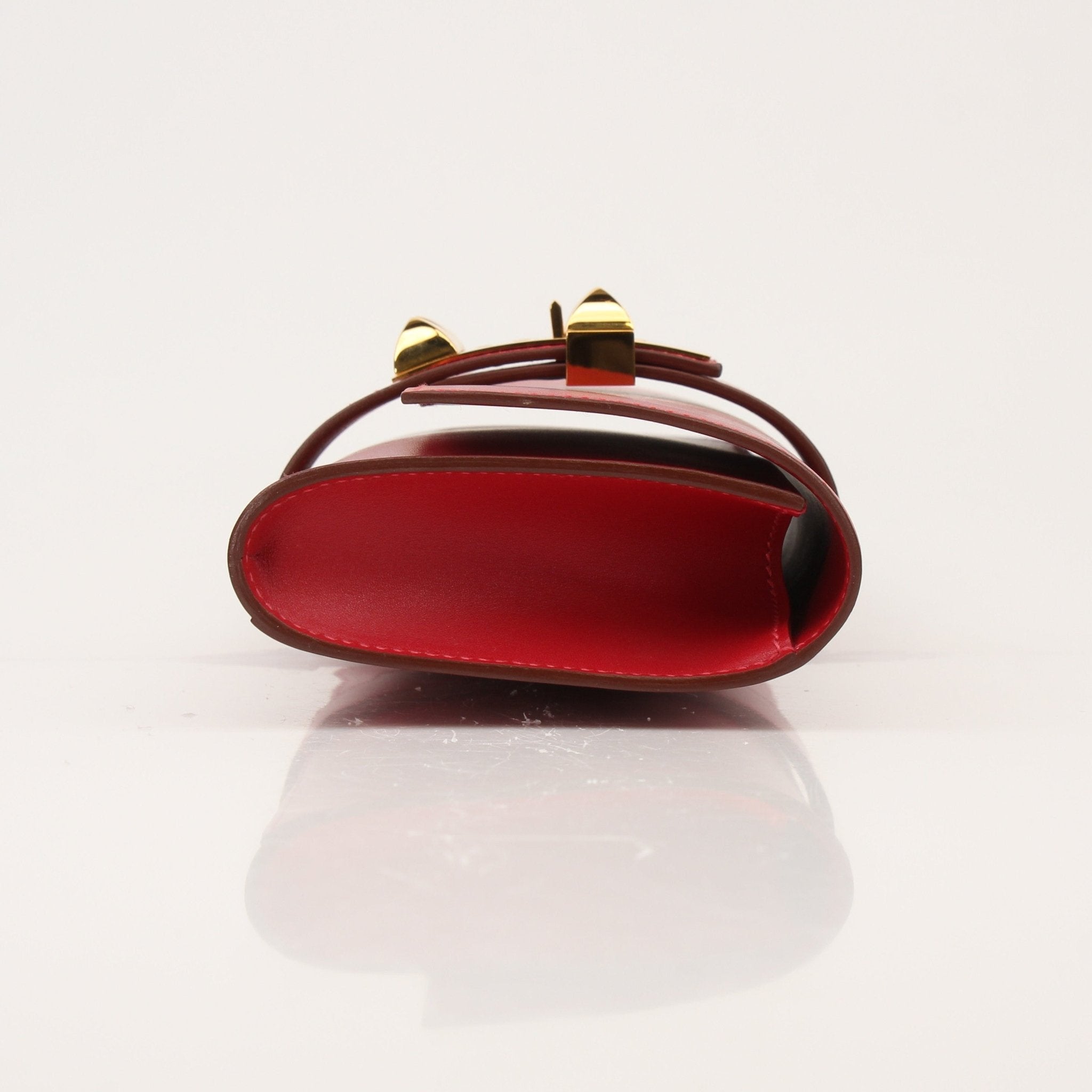 Hermès Médor 23 red clutch handbag with gold hardware, featuring a sleek design and textured leather finish.