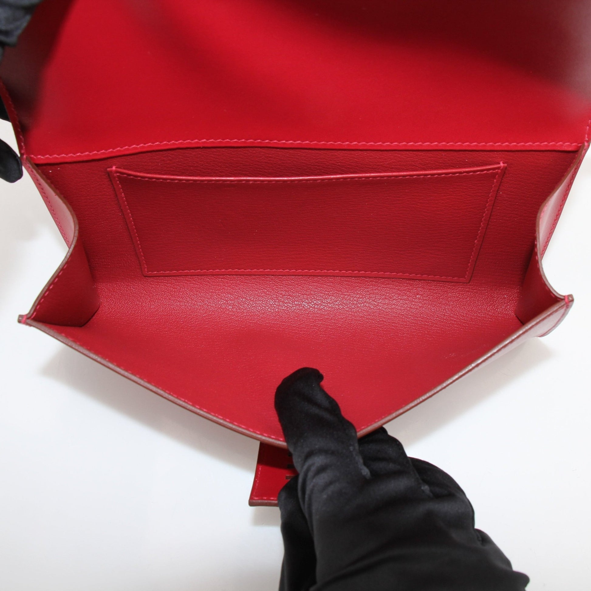Hermès Médor 23 red clutch handbag with gold-tone hardware, featuring a textured leather finish and compact, stylish design.