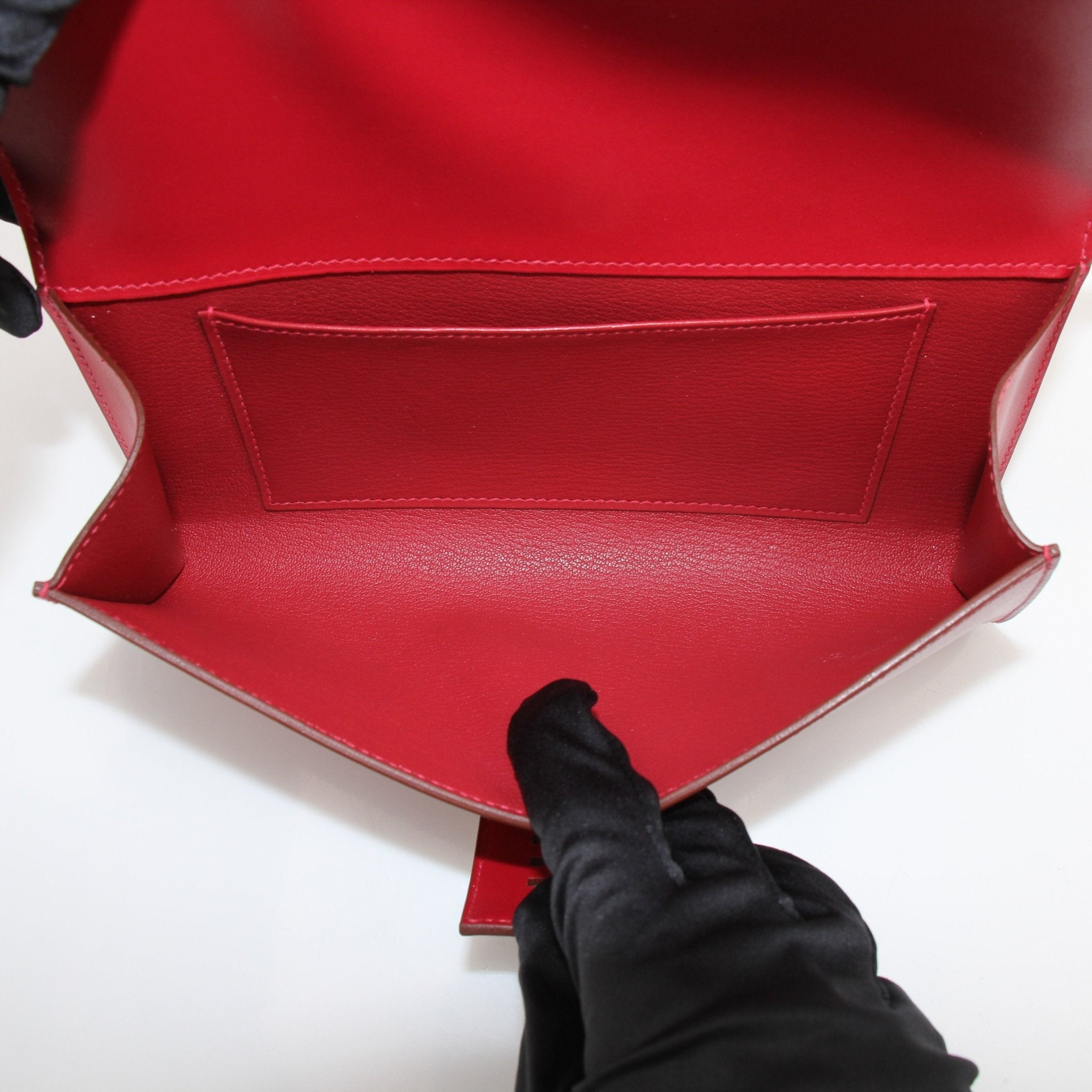 Hermès Médor 23 red clutch handbag with gold-tone hardware, featuring a textured leather finish and compact, stylish design.