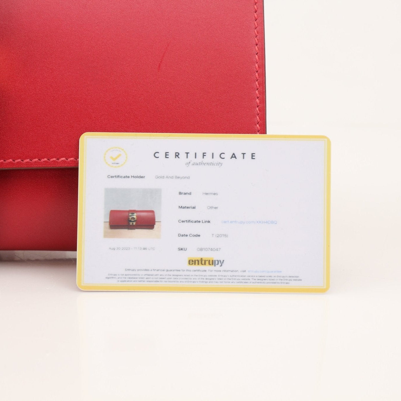 Hermès Médor 23 red clutch handbag with gold hardware, featuring a textured leather surface and compact, elegant design.