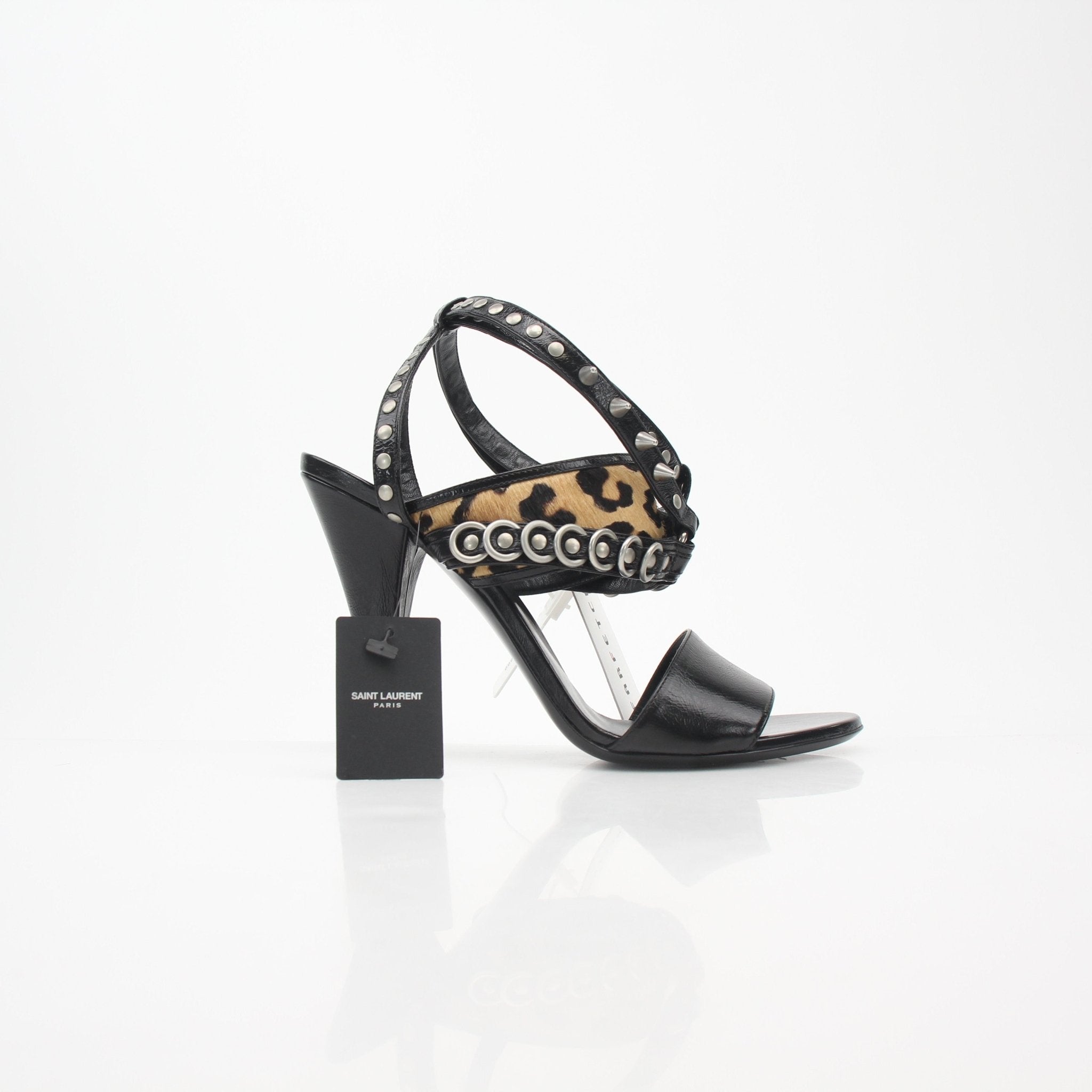 Black Saint Laurent studded leopard-print high-heel sandals with ankle straps and pointed toes, displayed on a neutral background.