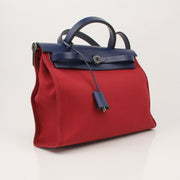 Hermès Herbag handbag with tan leather straps and canvas body, featuring gold hardware and classic design.