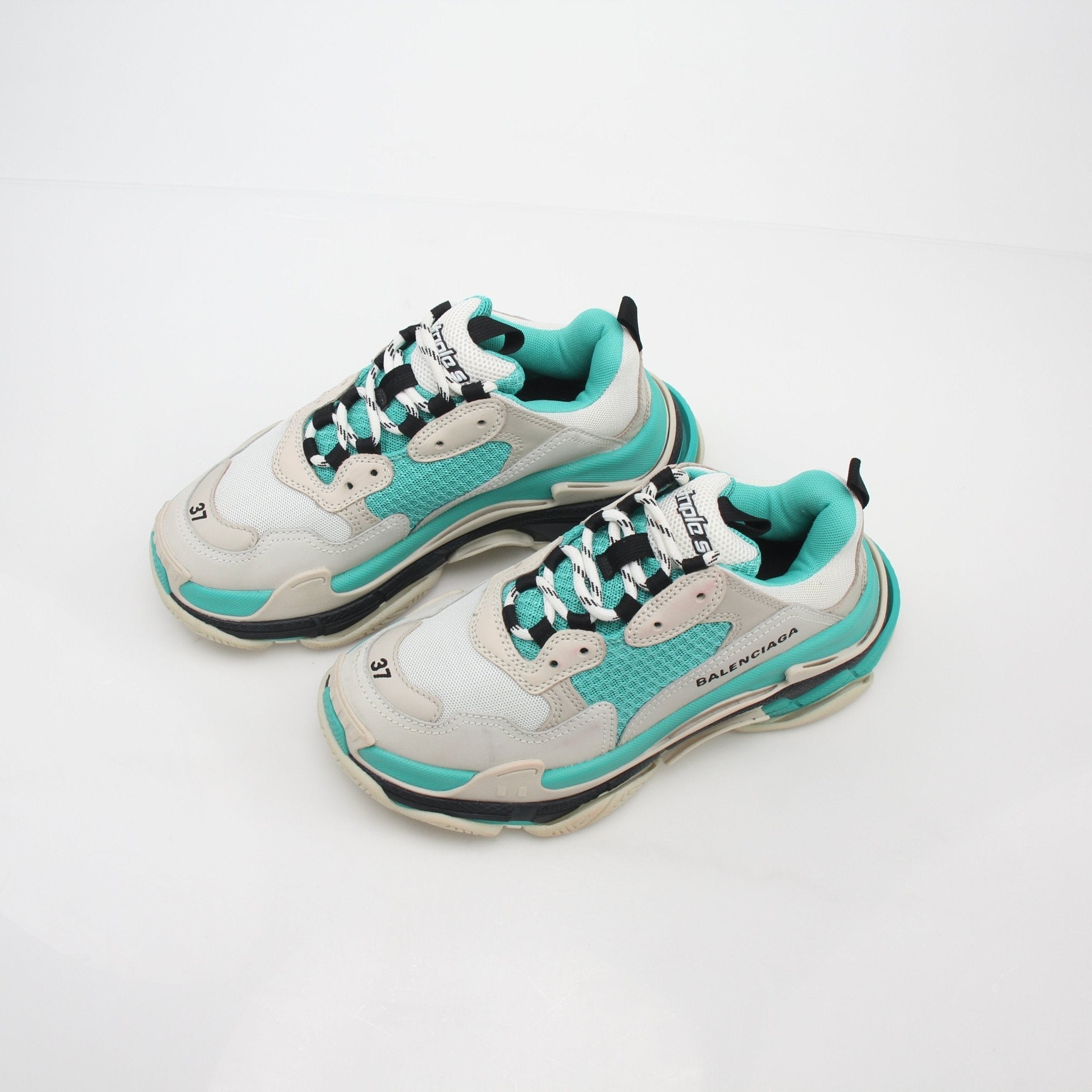 Turquoise Balenciaga Triple S Low-Top Sneakers with chunky sole and branding details, worn on feet showing casual style.