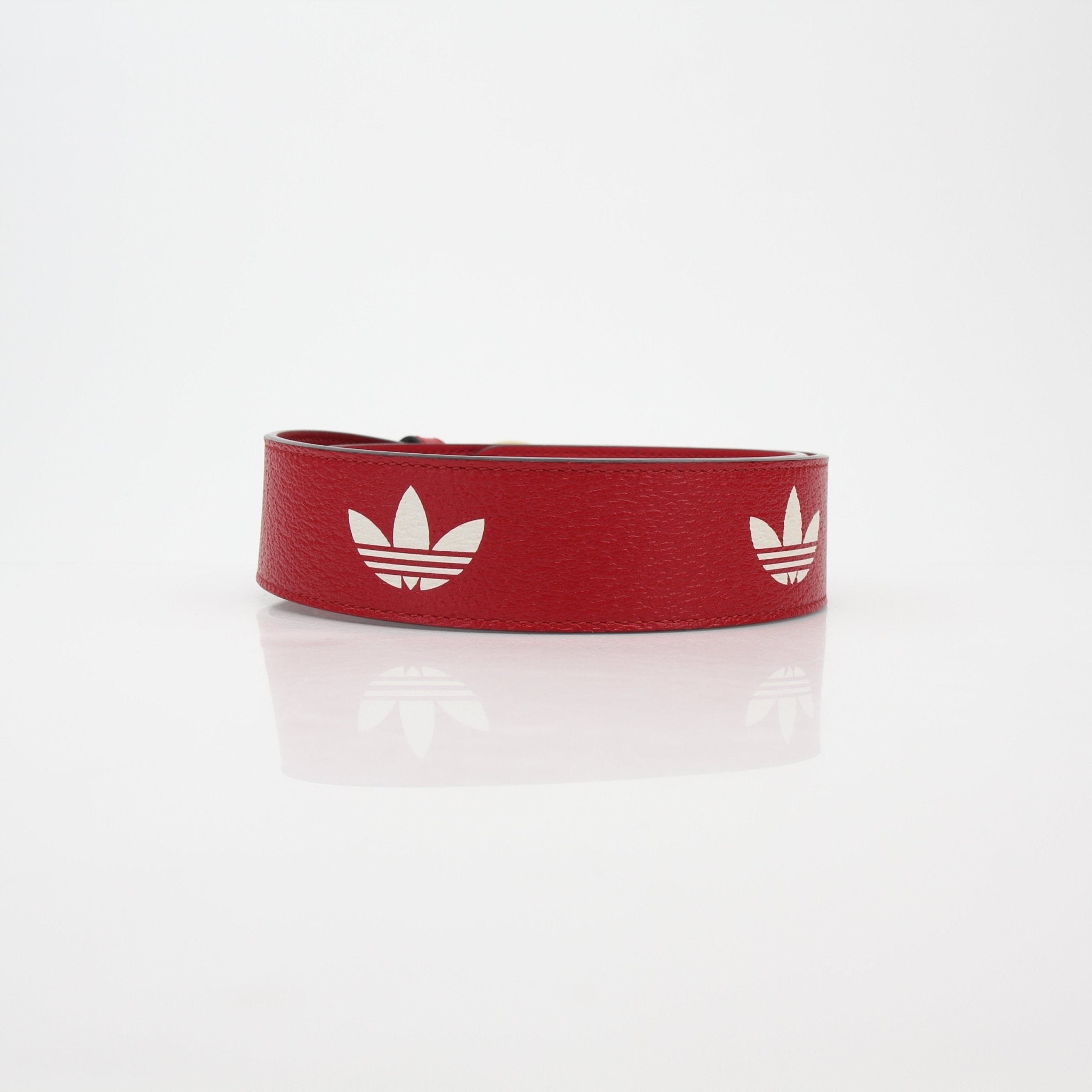 Red leather GG Marmont belt with gold accents from Adidas x Gucci accessories collection, featuring luxury branding and detailed craftsmanship.