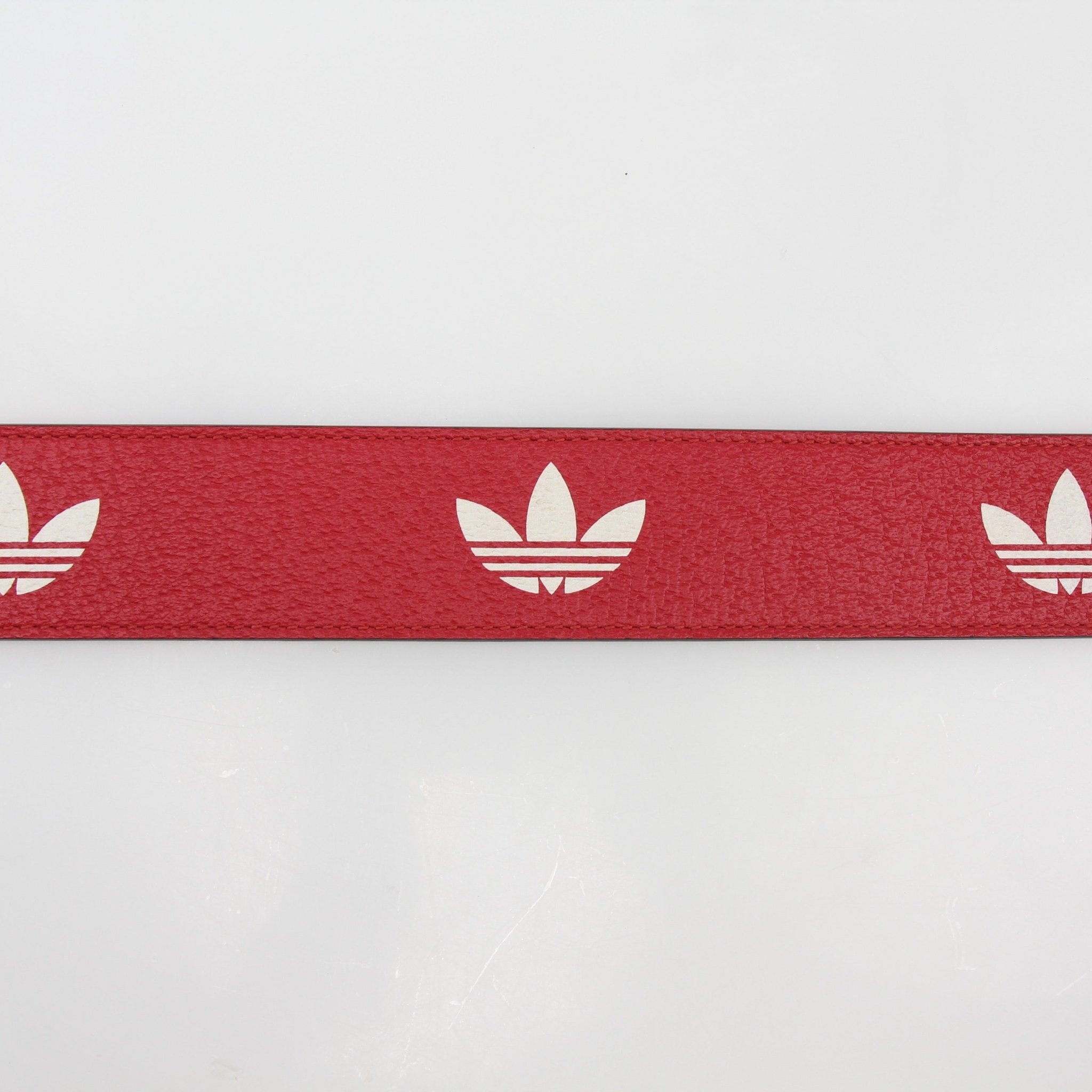 Red Gucci GG Marmont leather belt with gold hardware, stylish accessory from Adidas x Gucci collaboration.
