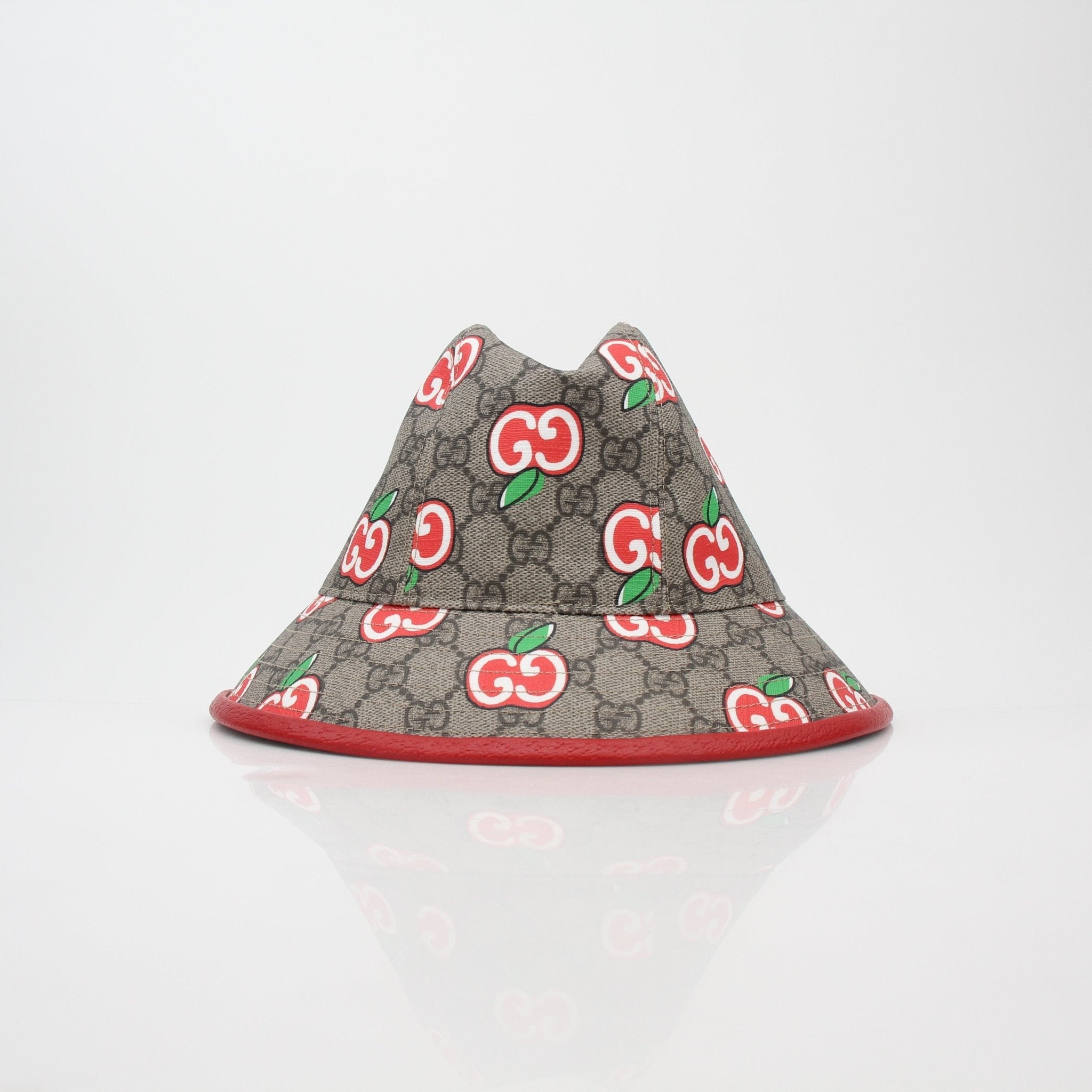 Gucci GG Supreme Apple print bucket hat, stylish accessories with branded pattern, worn by a model featuring a casual outdoor setting.