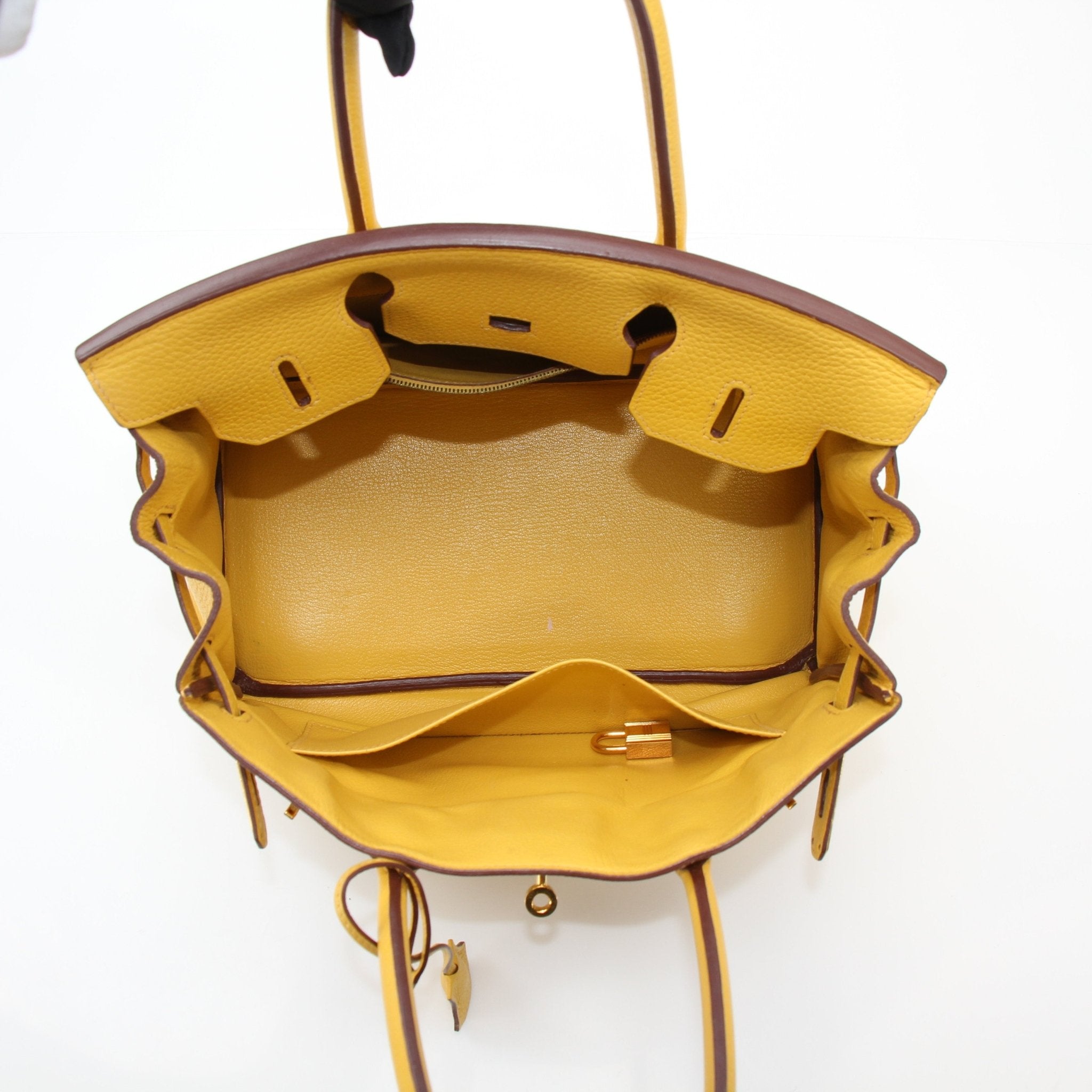 Hermès Birkin 30 yellow handbag with gold hardware, crafted from premium leather, displayed on a neutral background.