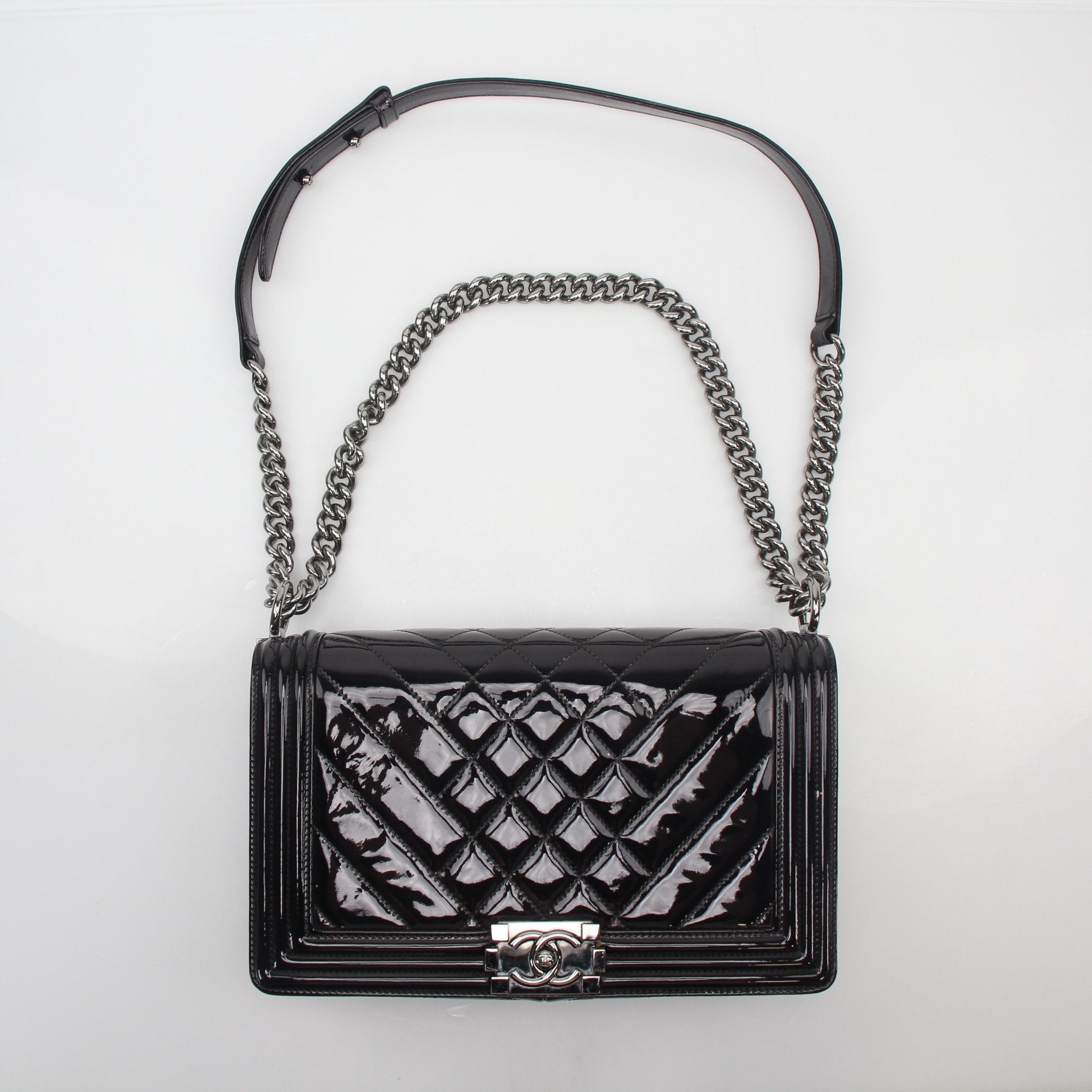 Black patent quilted Chanel Boy Flap Bag handbag with gold-tone hardware and signature quilting pattern.