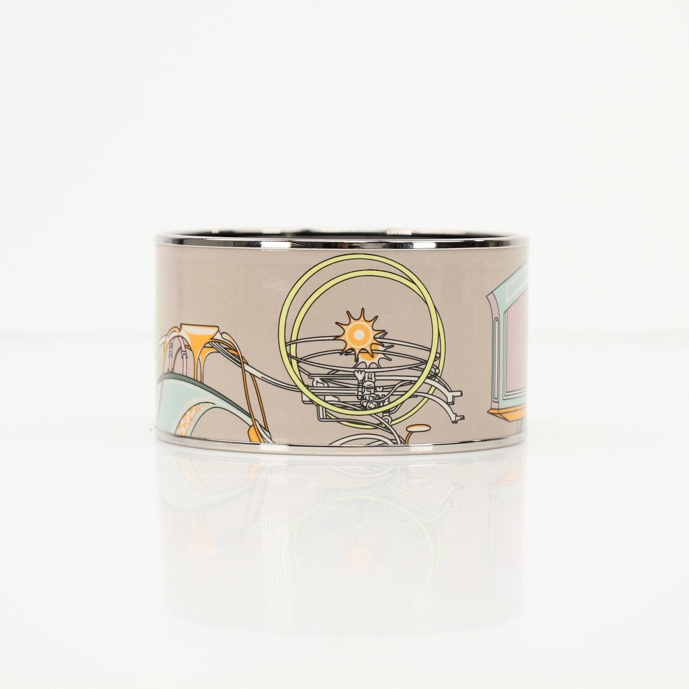 Hermès enamel cuff bracelet featuring colorful enamel in gold-tone jewelry design, worn on a wrist.