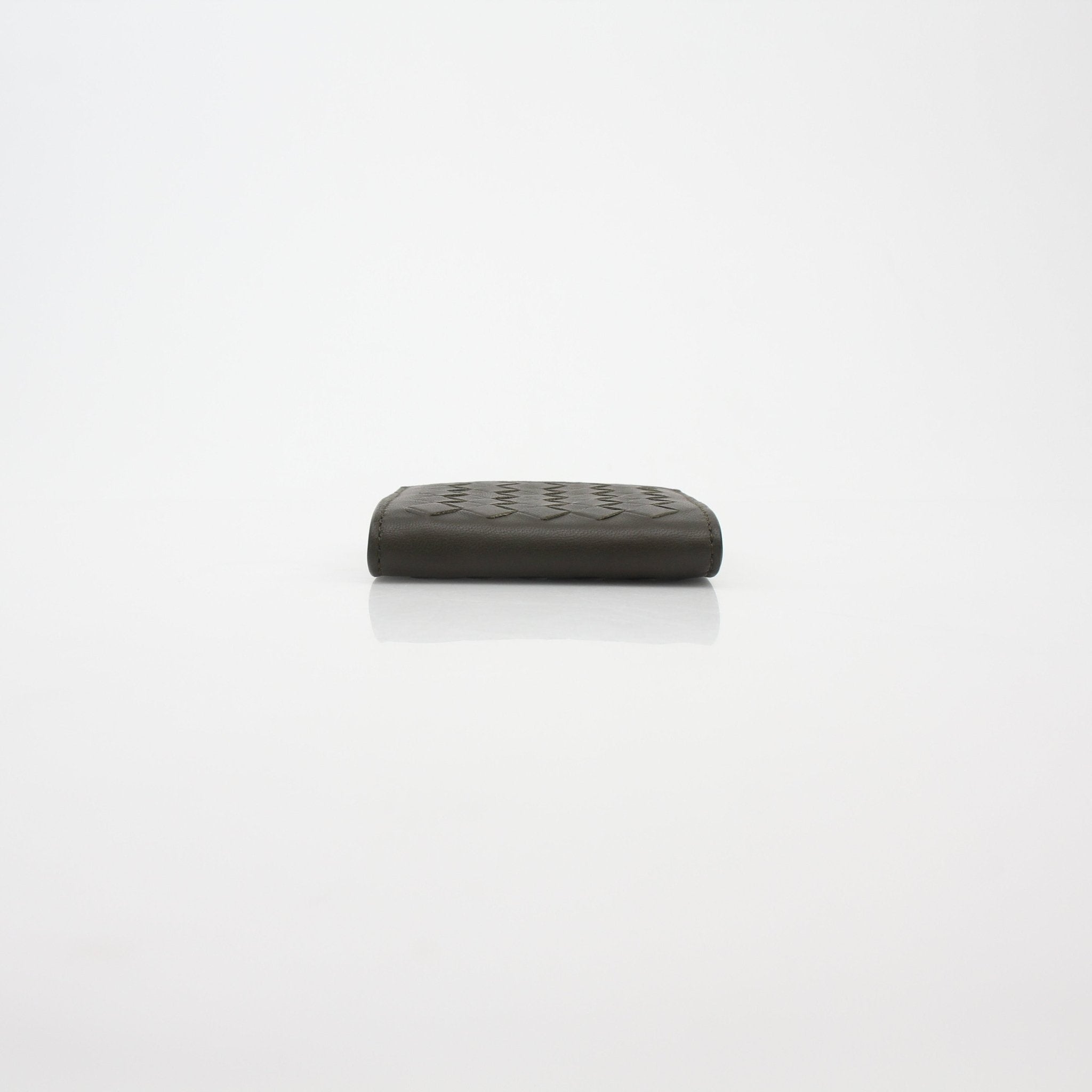 Dark green Bottega Veneta Intrecciato trifold coin purse wallet with woven leather design, compact and stylish.