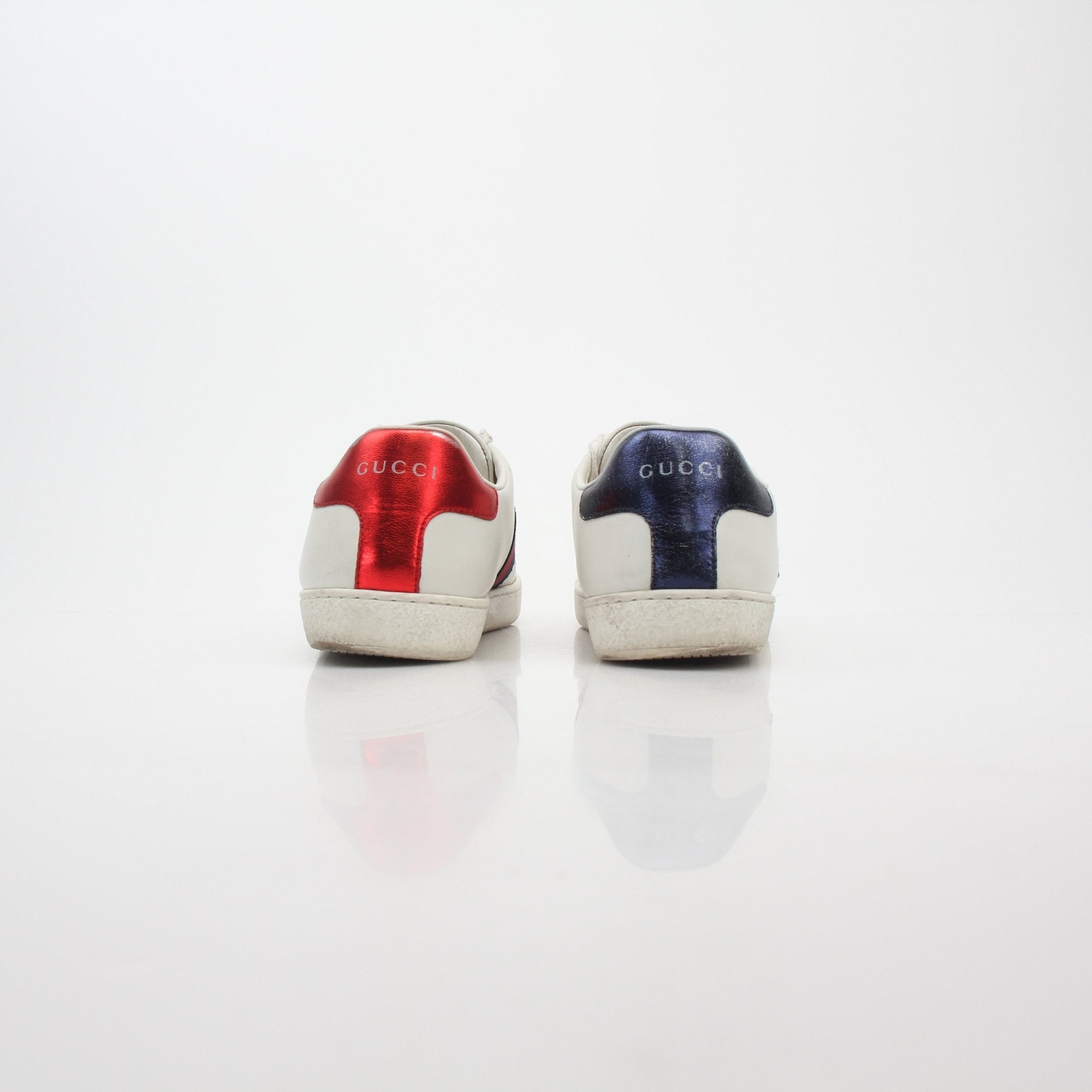 White Gucci Ace embroidered leather sneakers with gold accents, featuring signature design and stylish detailing.