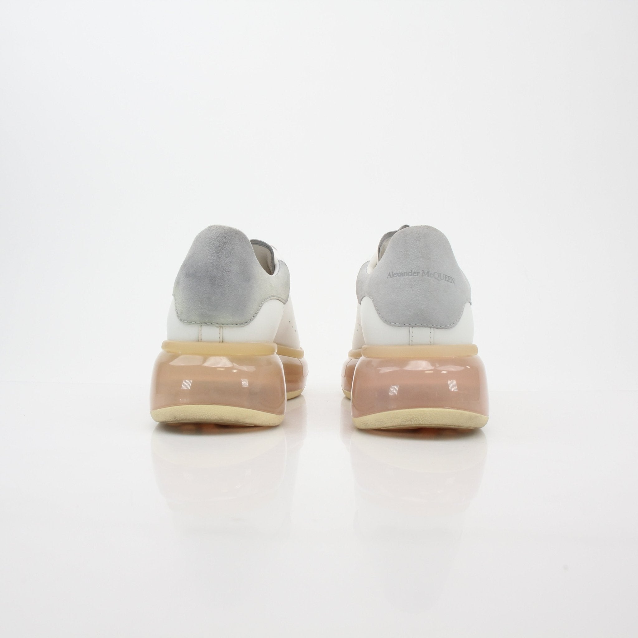Alexander McQueen white oversized sneakers with transparent soles, showcasing modern design and chunky shoe style.