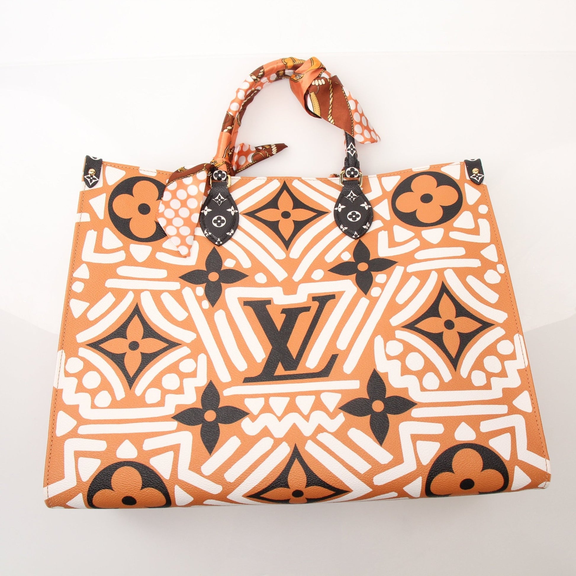 Louis Vuitton OnTheGo Crafty GM tote handbag in brown with gold hardware and leather handles, displayed against a neutral background.