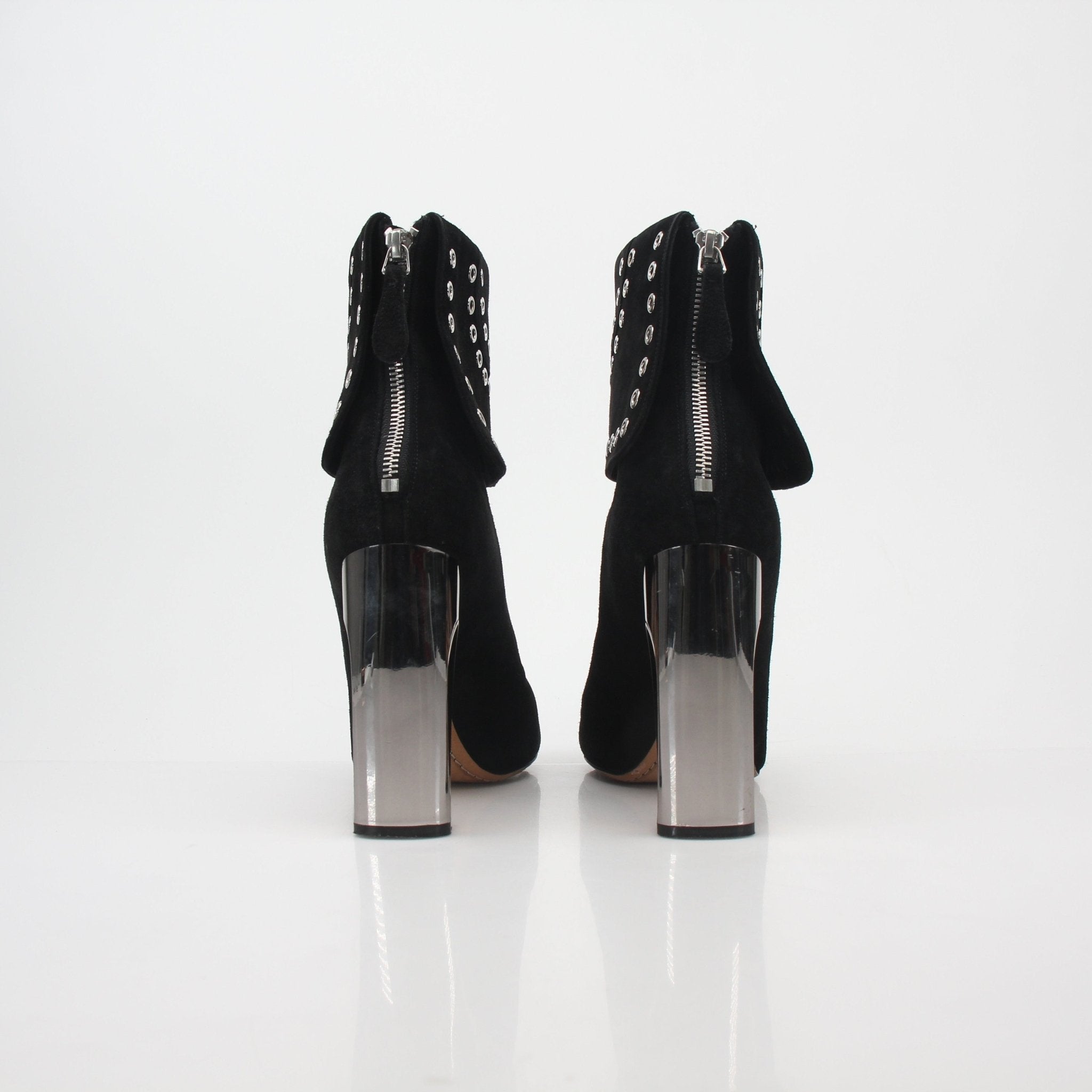 Black Alexander McQueen grommet fold-over ankle boots with chunky soles and silver hardware, worn with dark clothing.