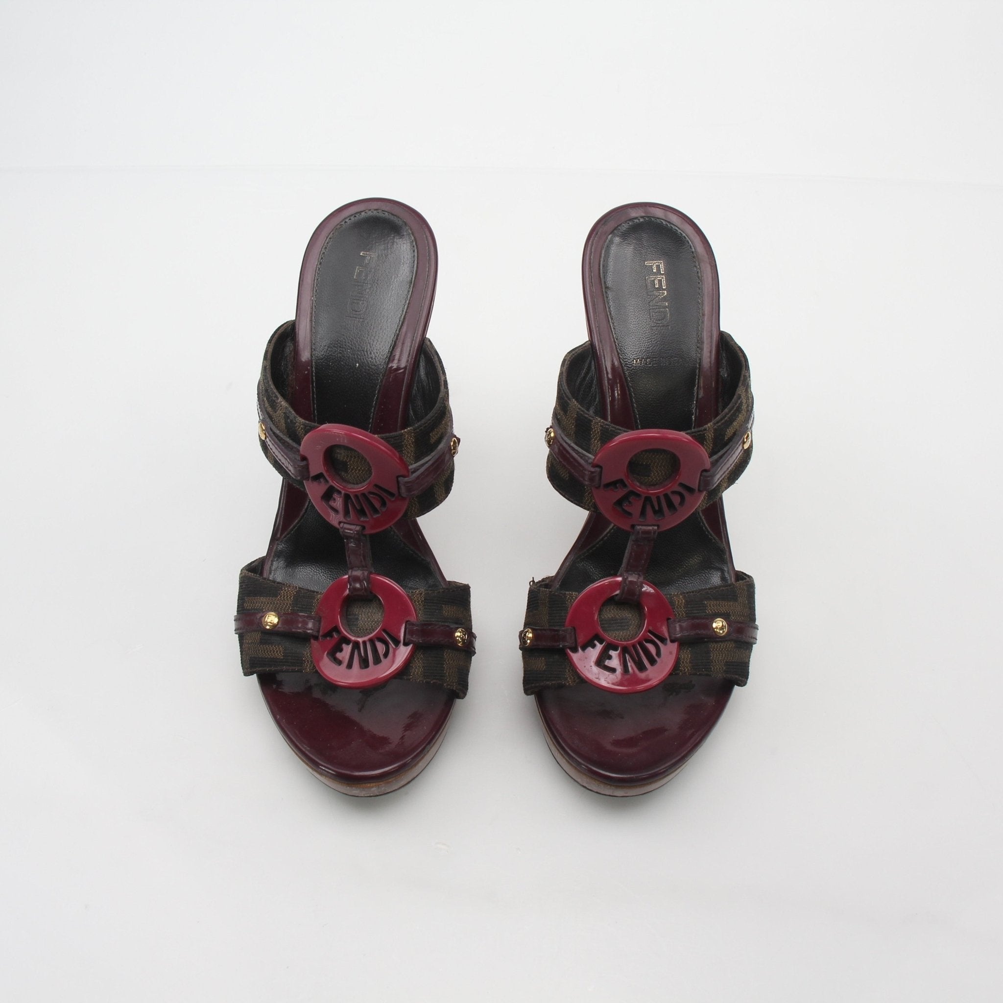 Fendi brown Zucca canvas platform sandals with heels, featuring ankle straps and signature print, on a neutral background.