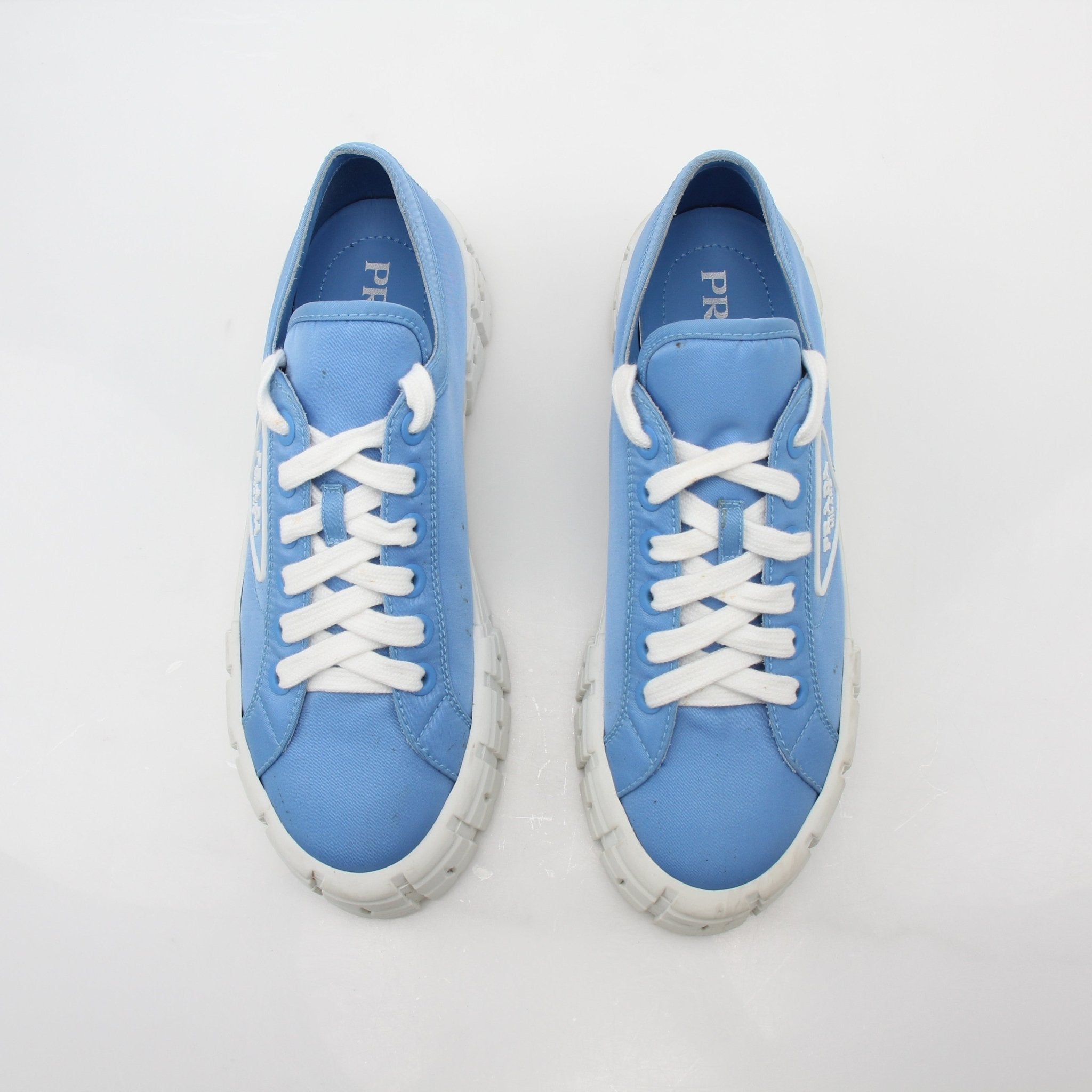 Gold & Beyond Prada light blue double wheel low top sneakers showing stylish shoes with white soles and logo details.