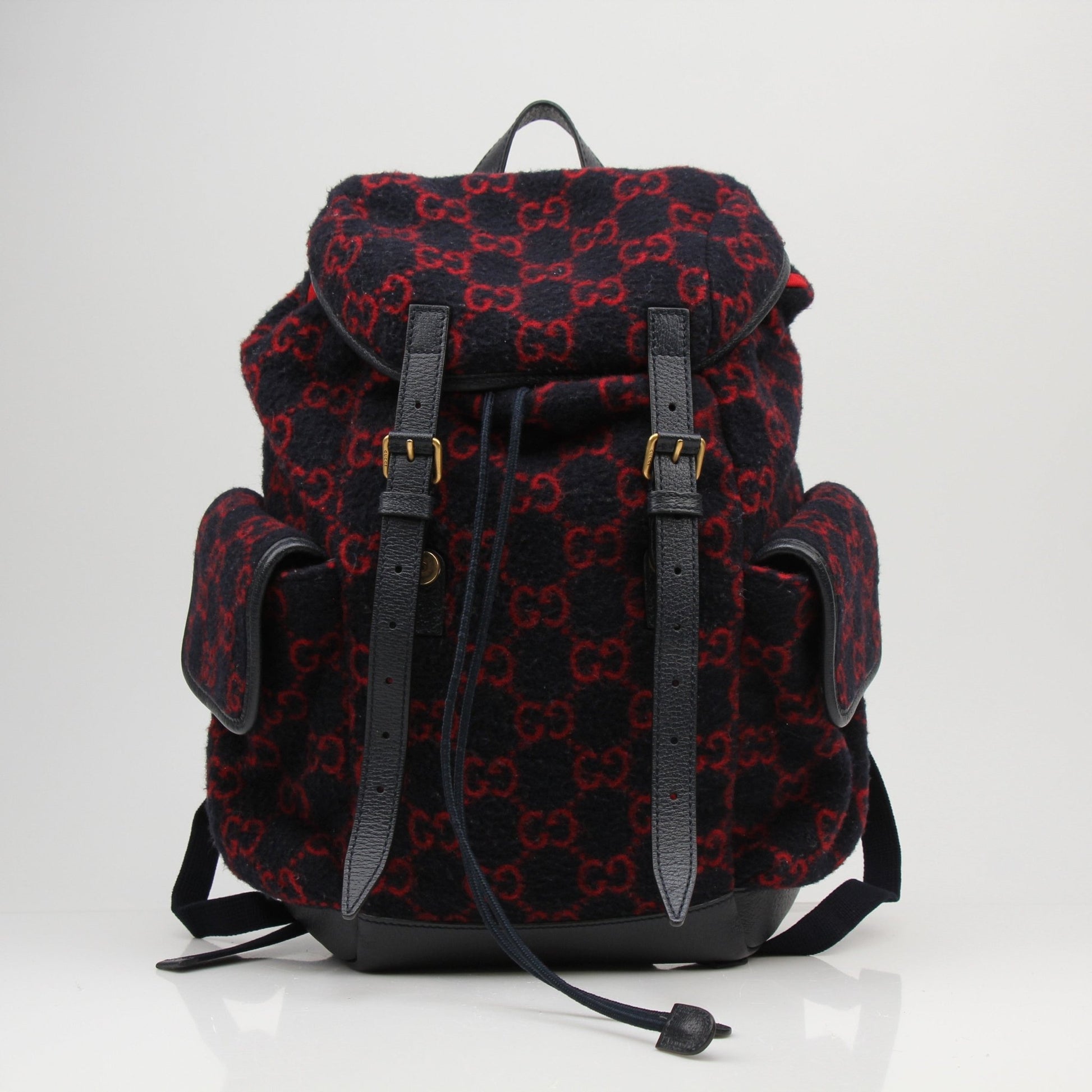 Gucci GG Monogram backpack handbag with gold accents and adjustable straps, featuring signature monogram fabric and leather details.