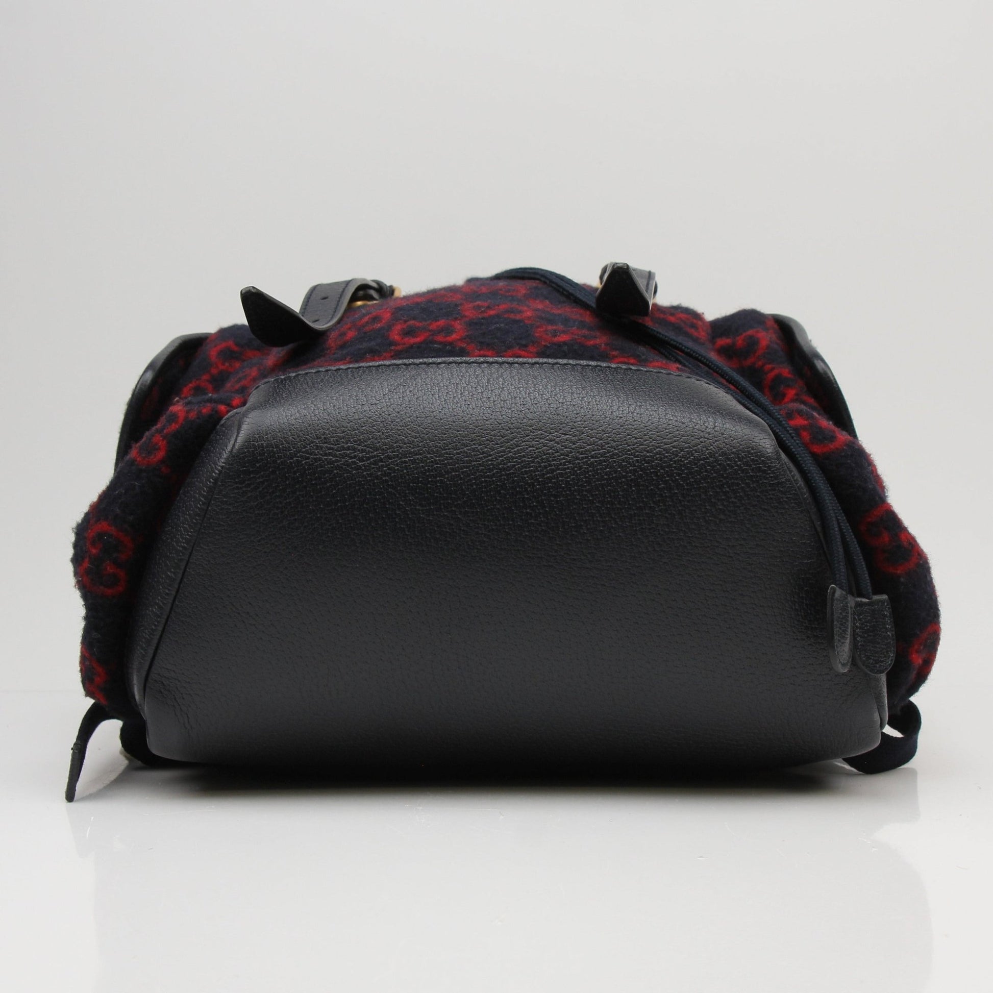 Gucci GG Monogram backpack handbag with gold accents, featuring signature monogram pattern and adjustable straps.