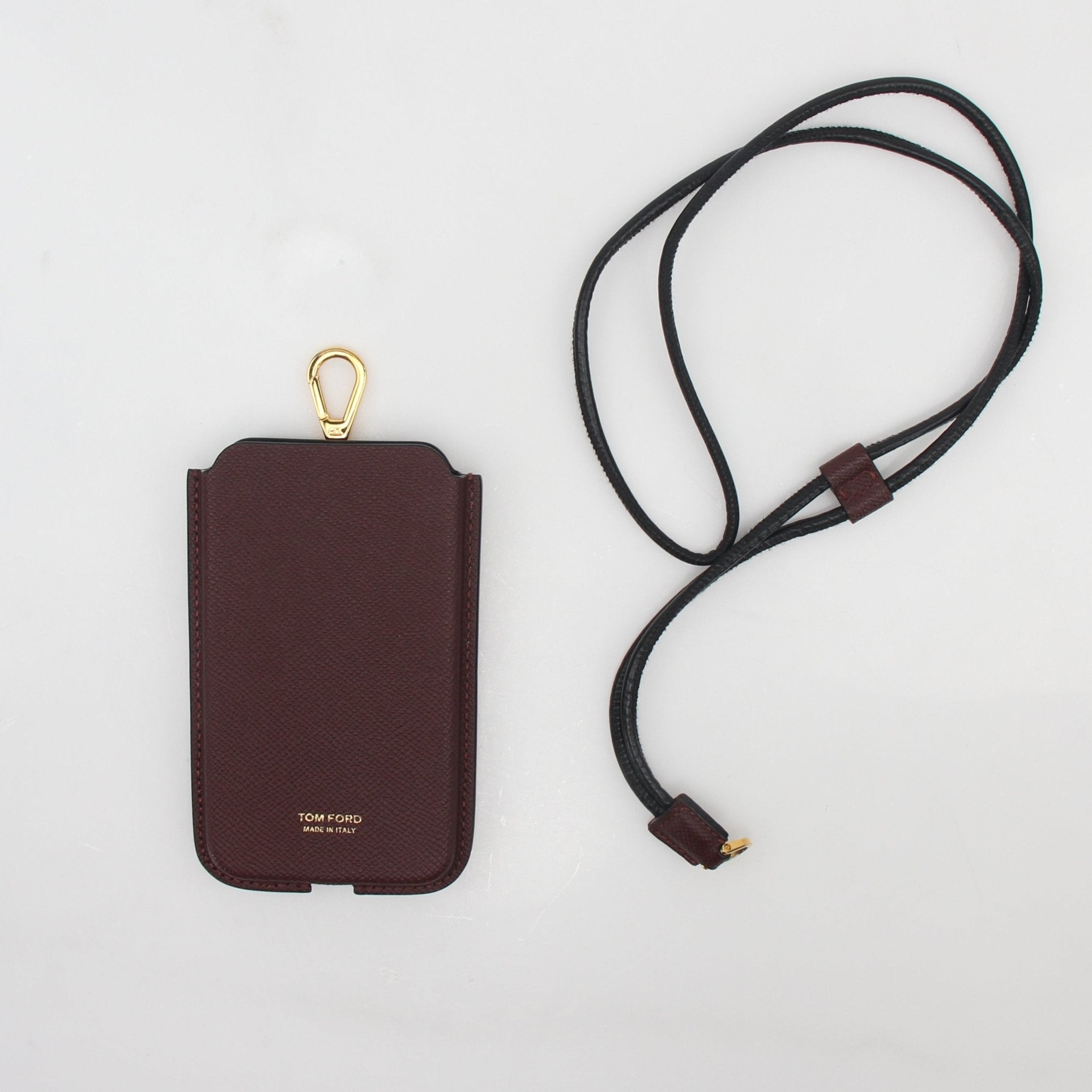 Tom Ford burgundy leather phone case with attached lanyard, designed as a stylish handbag accessory.