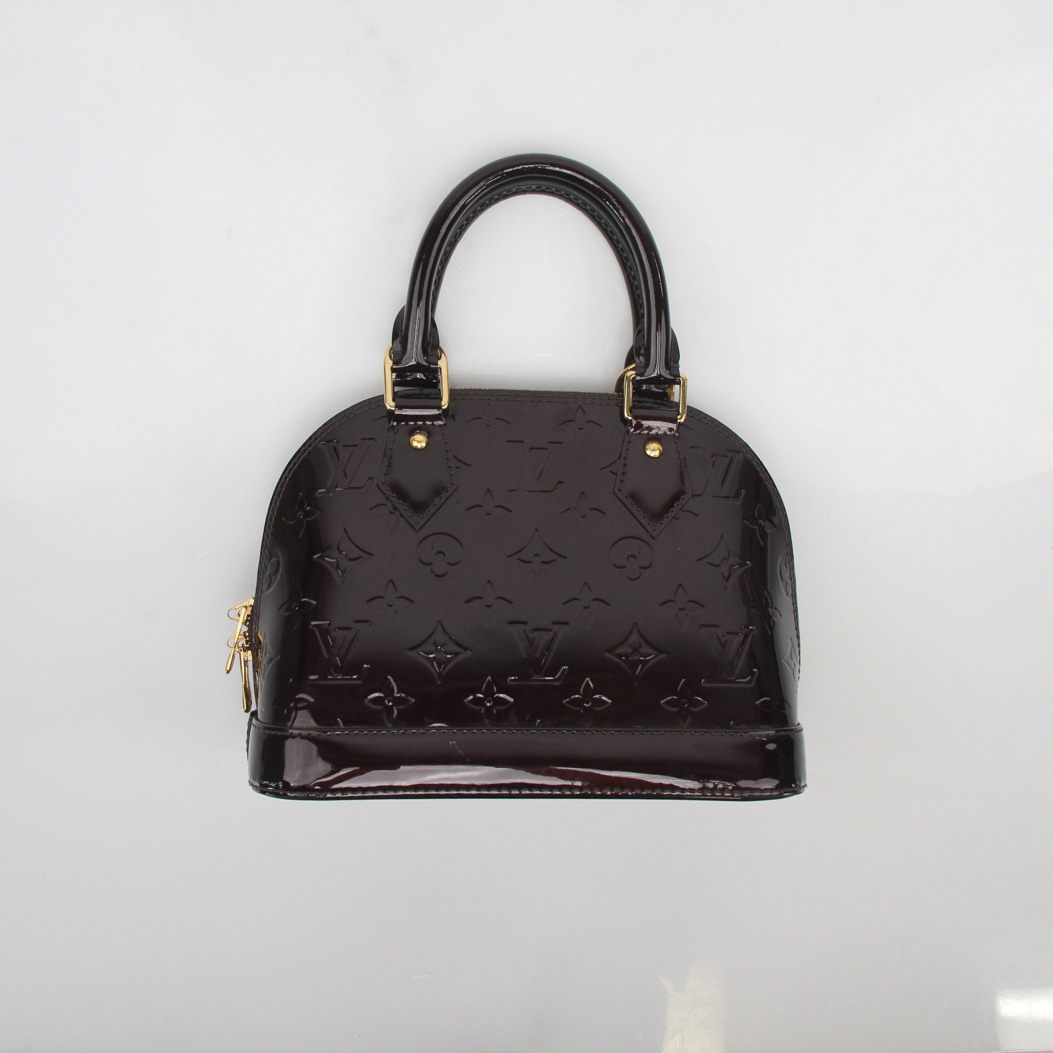 Louis Vuitton Monogram Vernis Alma BB handbag with gold-tone hardware, featuring a glossy monogram pattern and structured design.