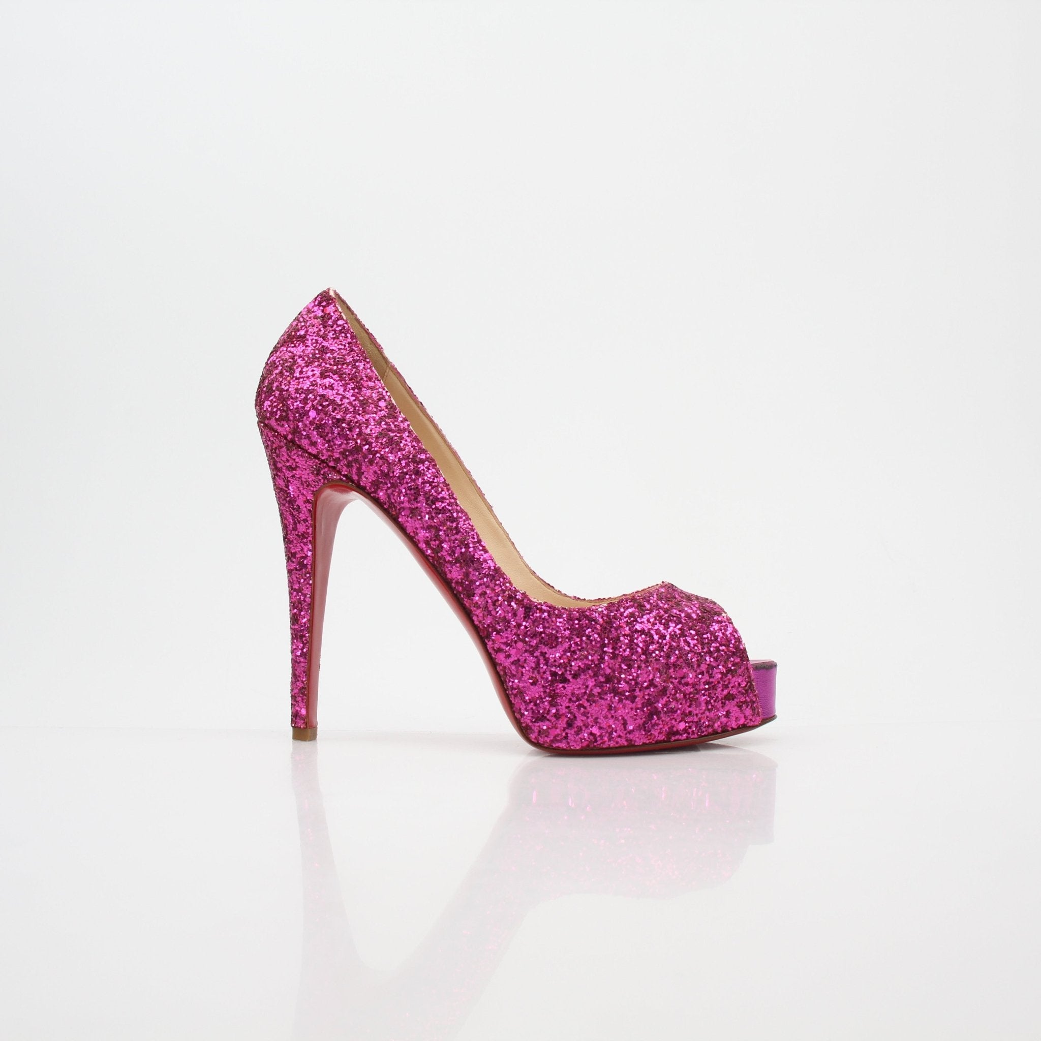 Pink glitter Christian Louboutin Very Privé platform heels with stiletto heels and signature red soles, displayed on a neutral background.