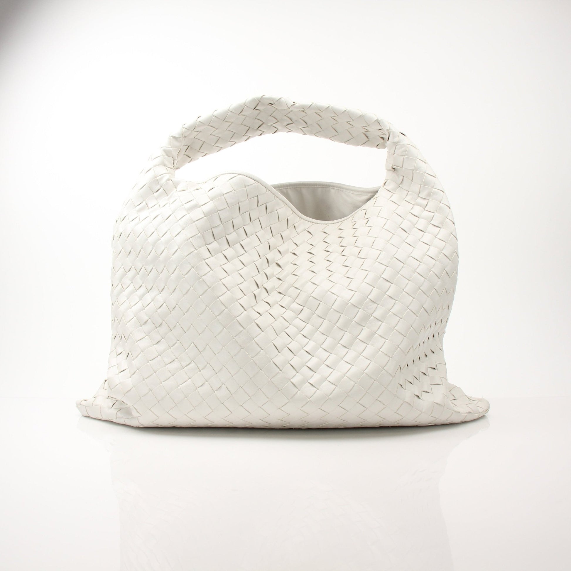Large white Bottega Veneta Intrecciato leather hobo bag with woven design, spacious and stylish, shown resting on a neutral background.