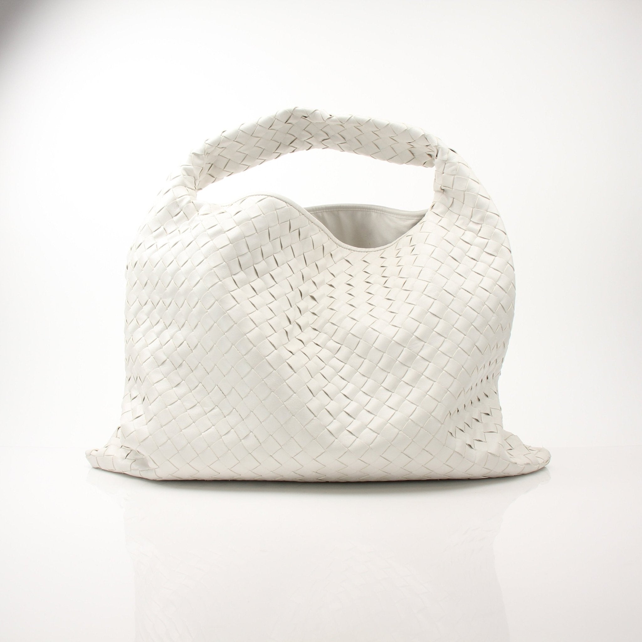 Large white Bottega Veneta Intrecciato leather hobo bag with woven design, spacious and stylish, shown resting on a neutral background.