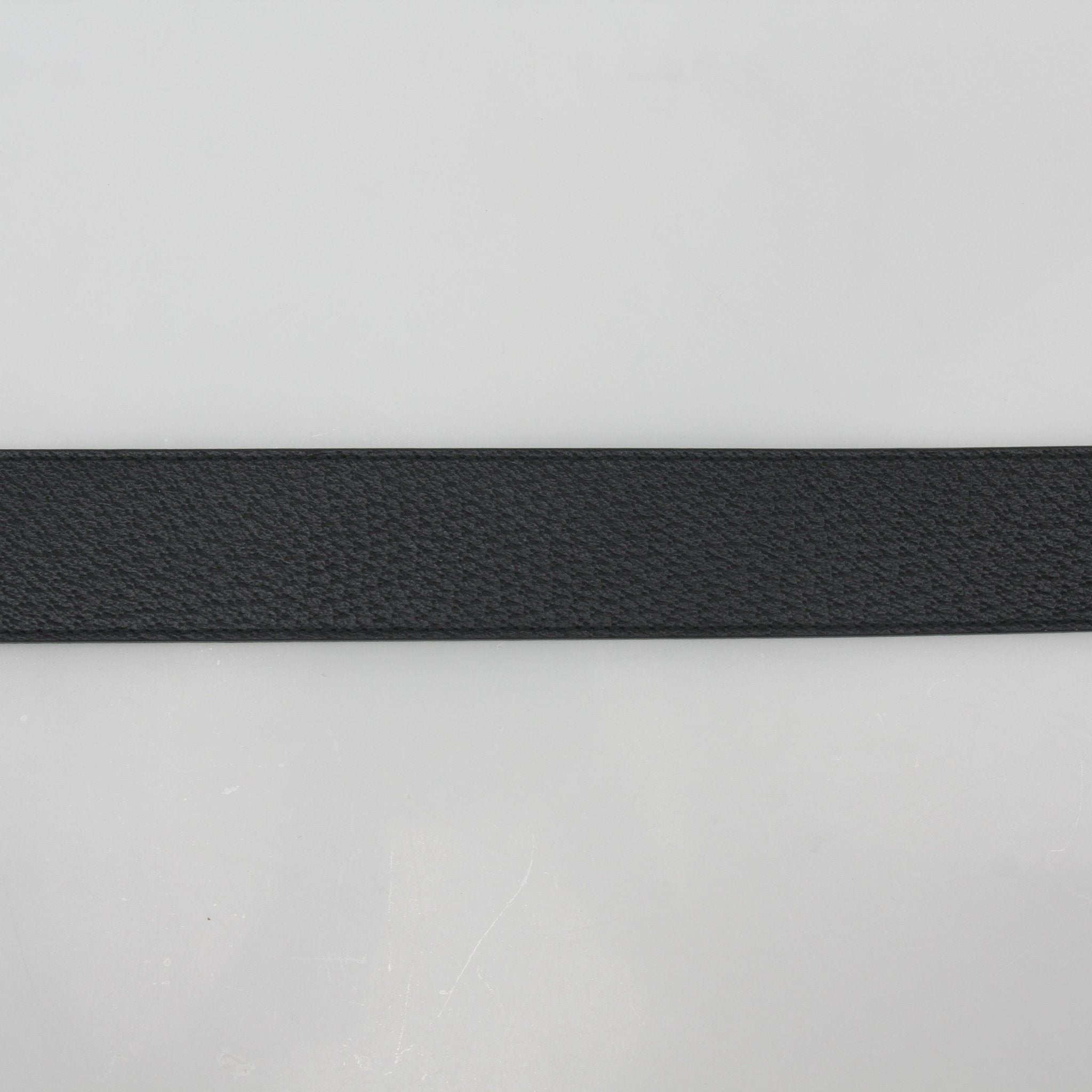 Black leather Gucci GG Marmont belt with gold-toned hardware, displayed on a neutral background.
