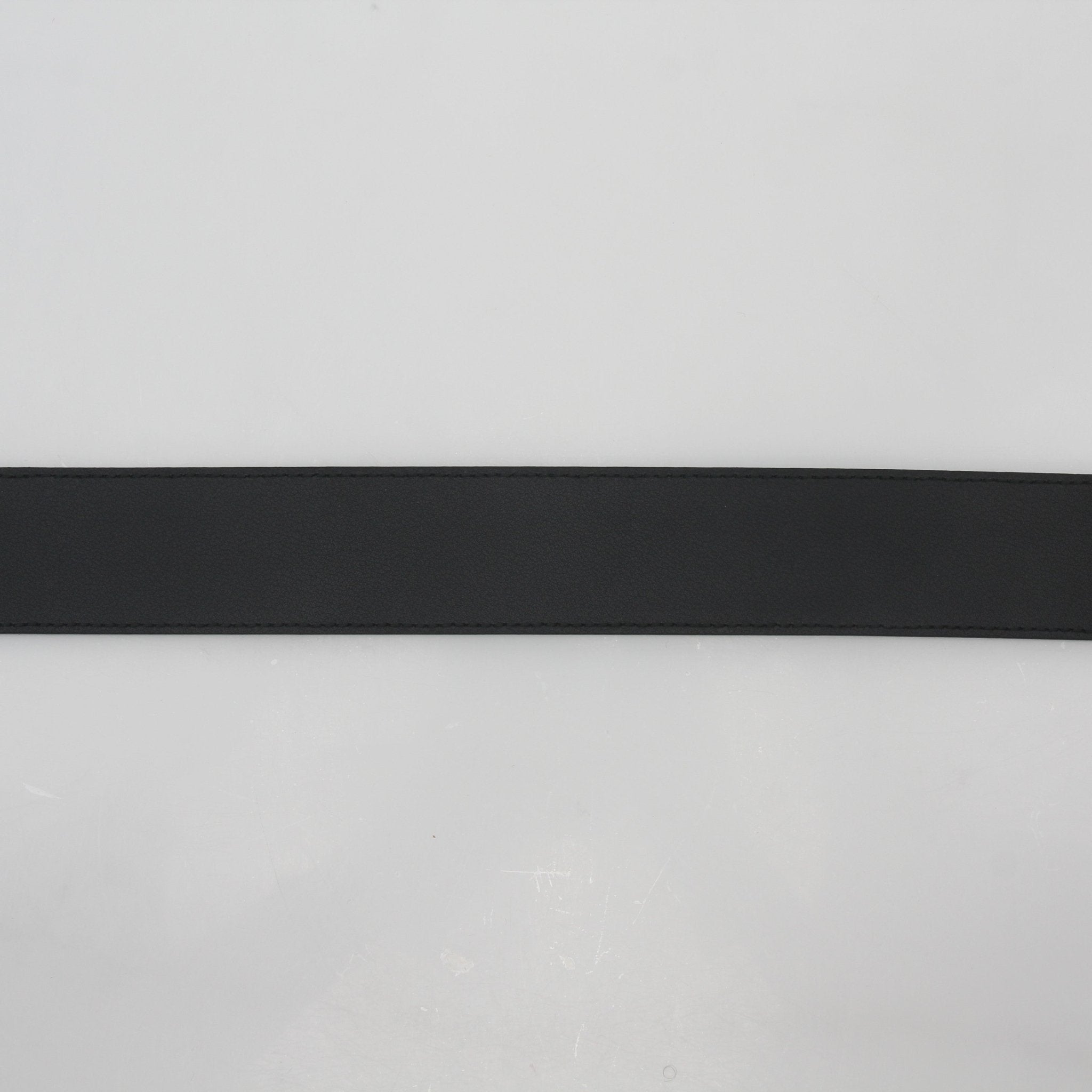 Black leather Gucci GG Marmont belt with gold hardware, showcasing the iconic double G logo and adjustable strap.