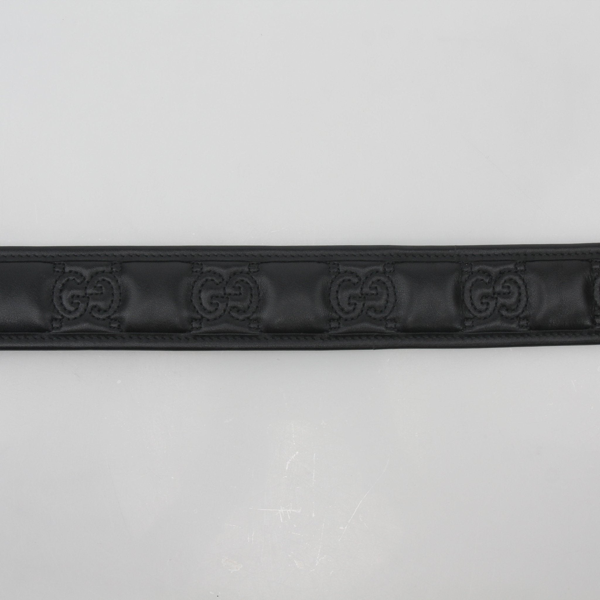 Black Gucci GG Marmont leather belt with gold-tone buckle, featuring signature logo and elegant design, displayed on a neutral background.